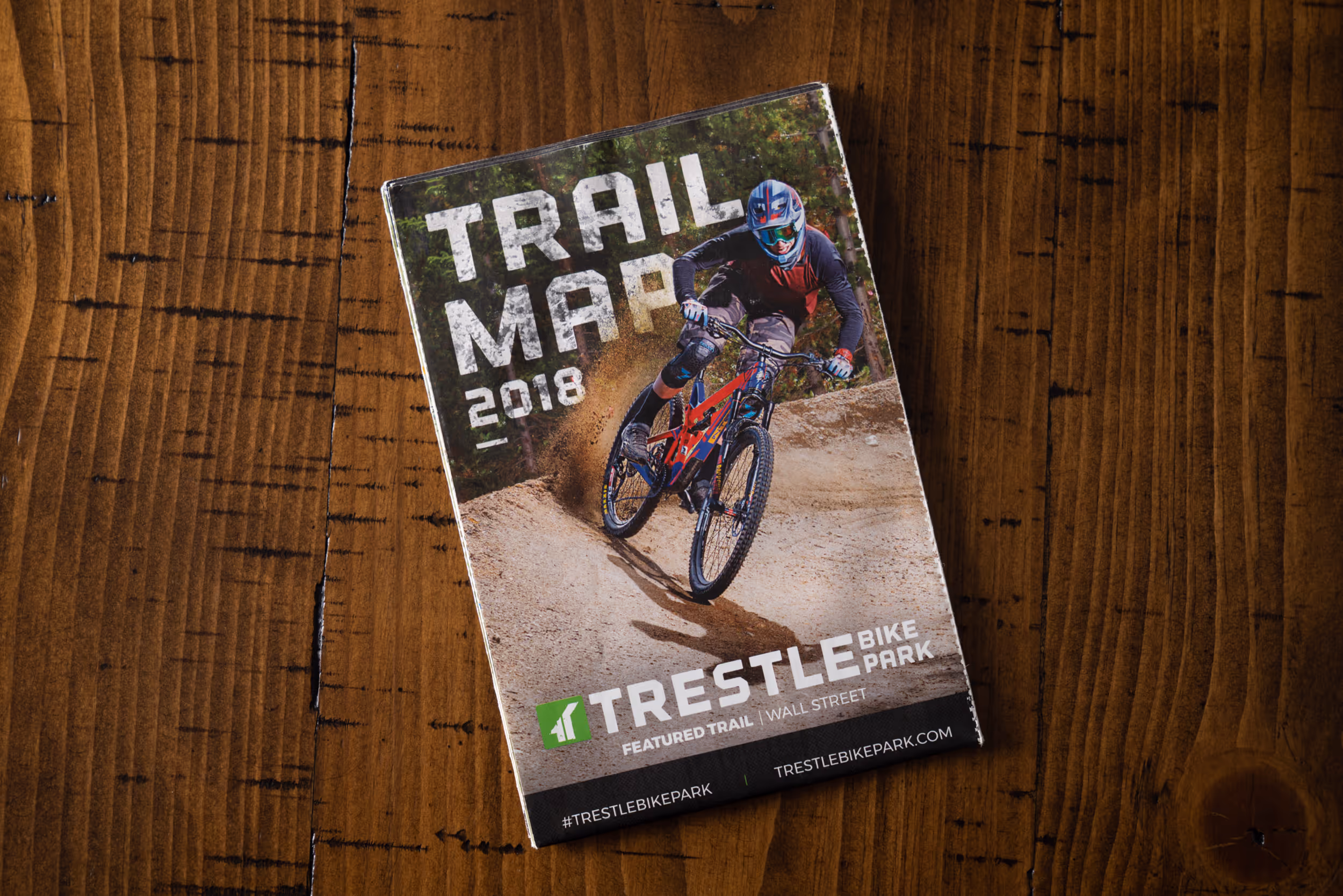 A image of a mountain biker hitting a berm as the image on the front of a trail map 