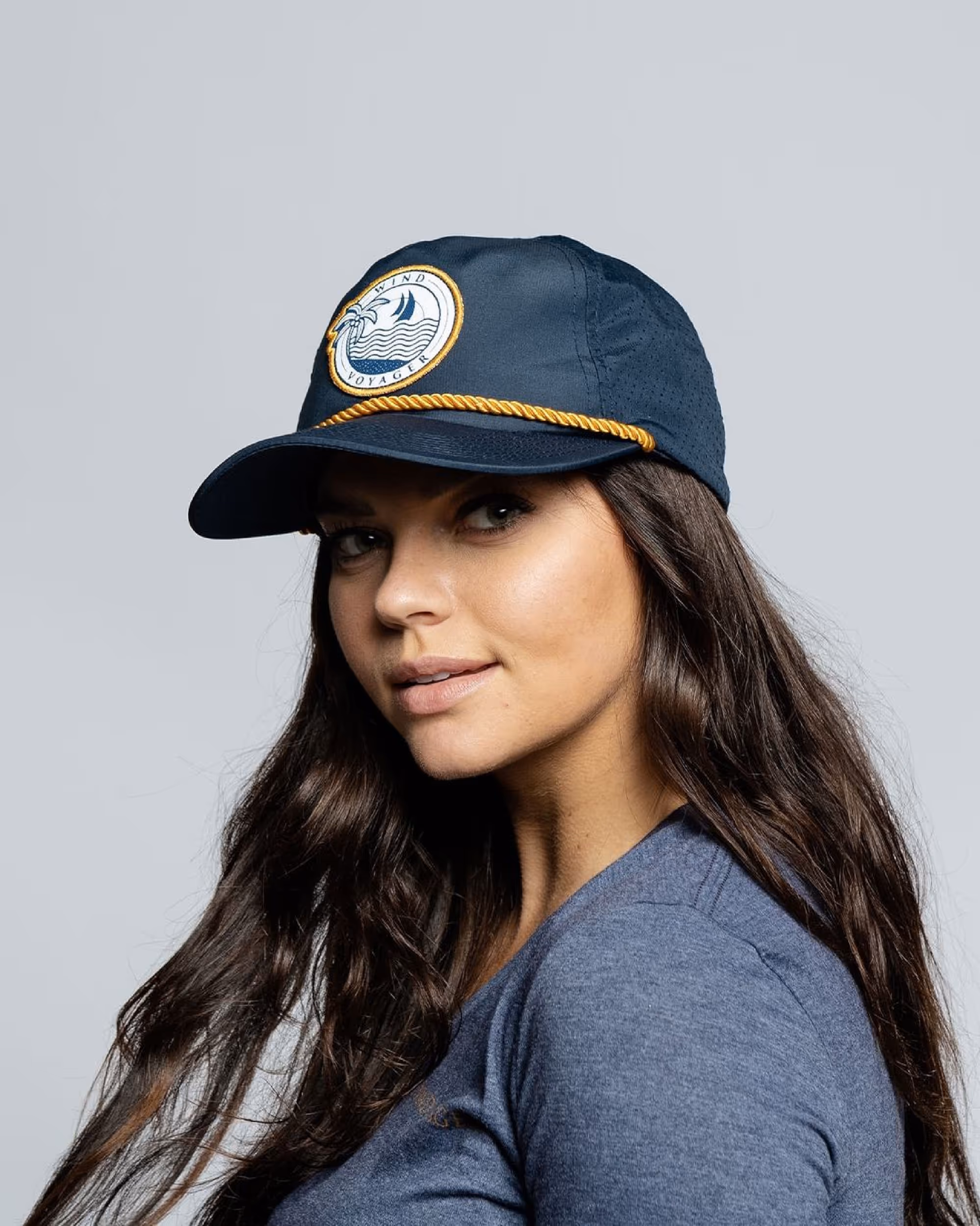 Woman wearing a dark blue Wind Voyager hat with gold accents 