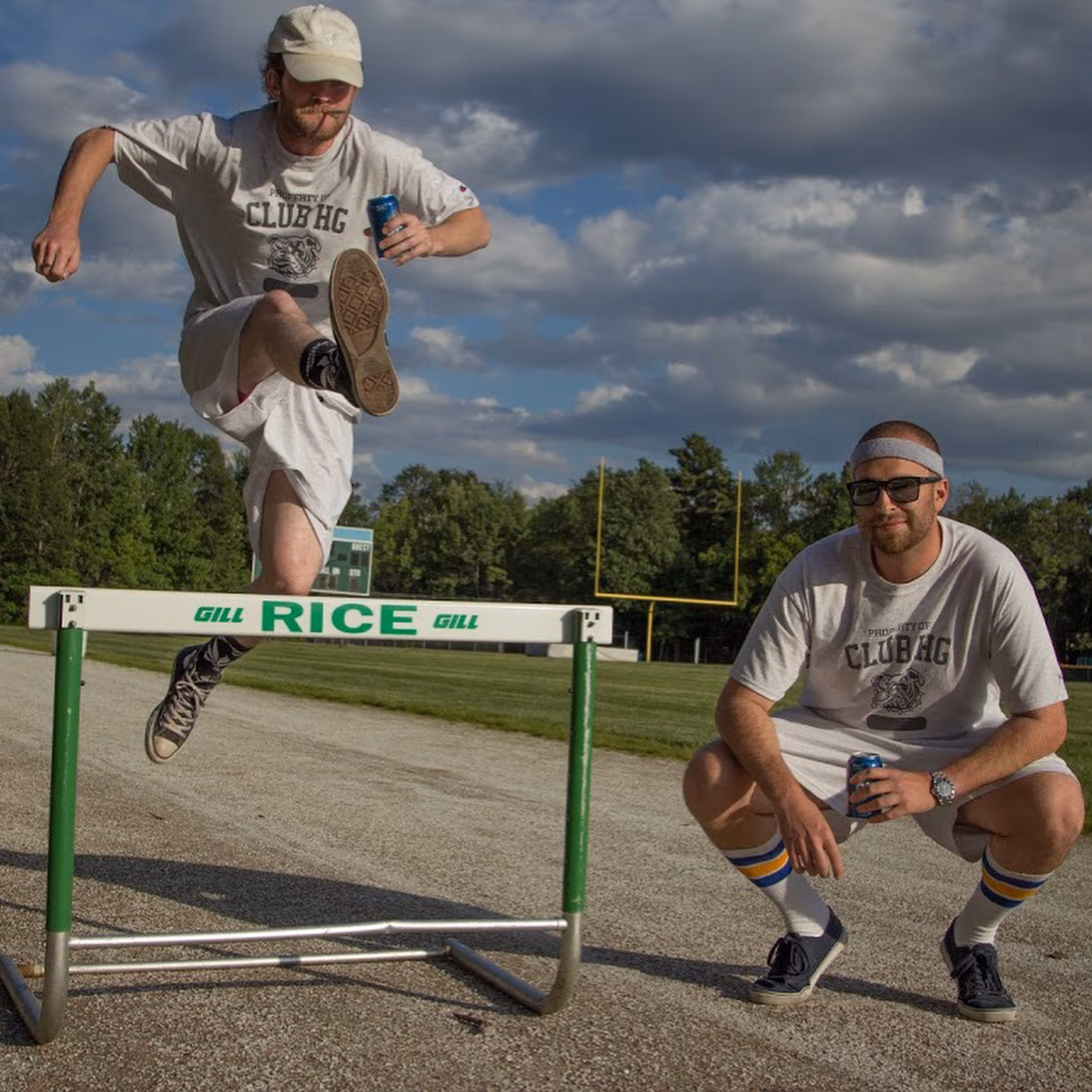2 men playing around on the track field with HG ski tshirts 