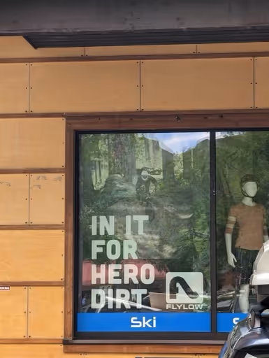 An advertisement displayed in a sporting goods store window in Jackson, WY displaying forested mountain biking image that Charles Stemen Studio captured. 