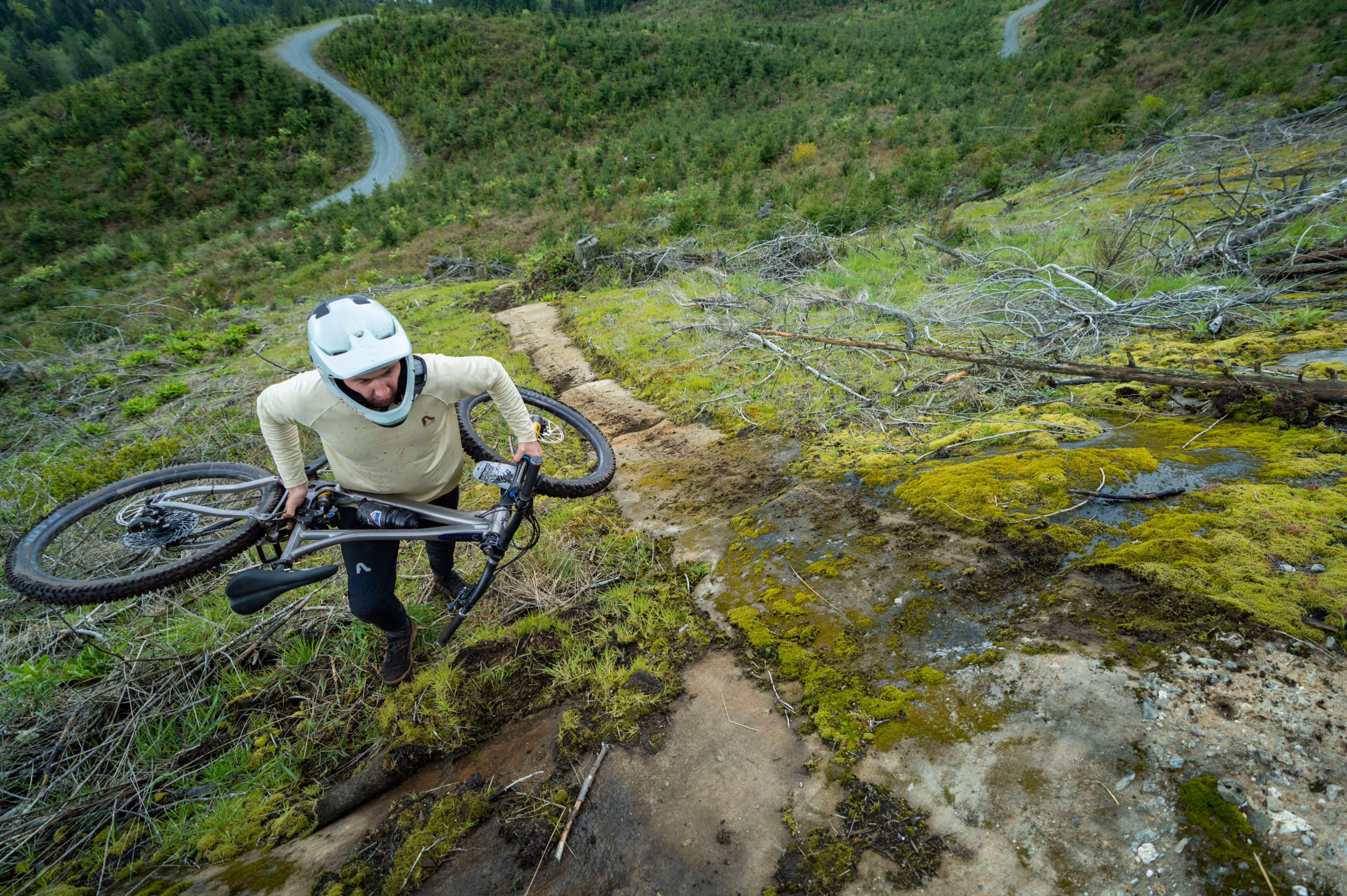 A mountain biker hiking their bike up a steep section of trail 