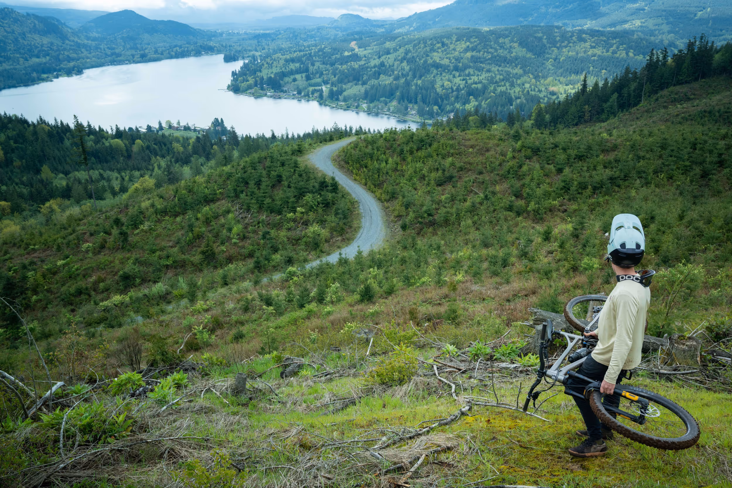 A mountain biker scoping a trail that overlooks a lake 