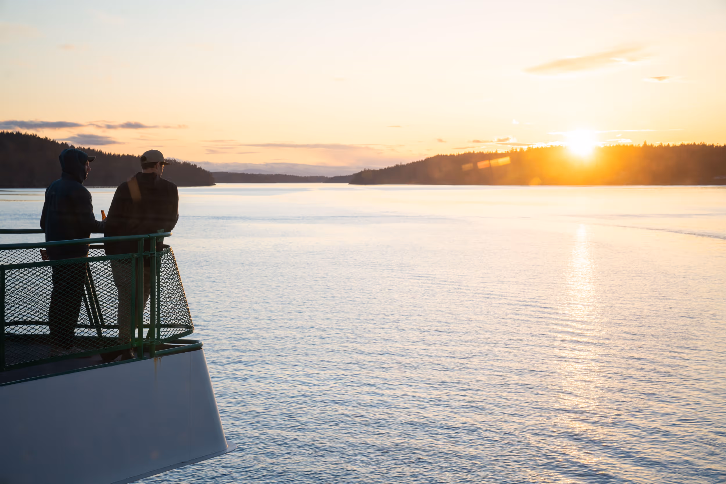 Some men overlooking the ocean off the back of a ferry 