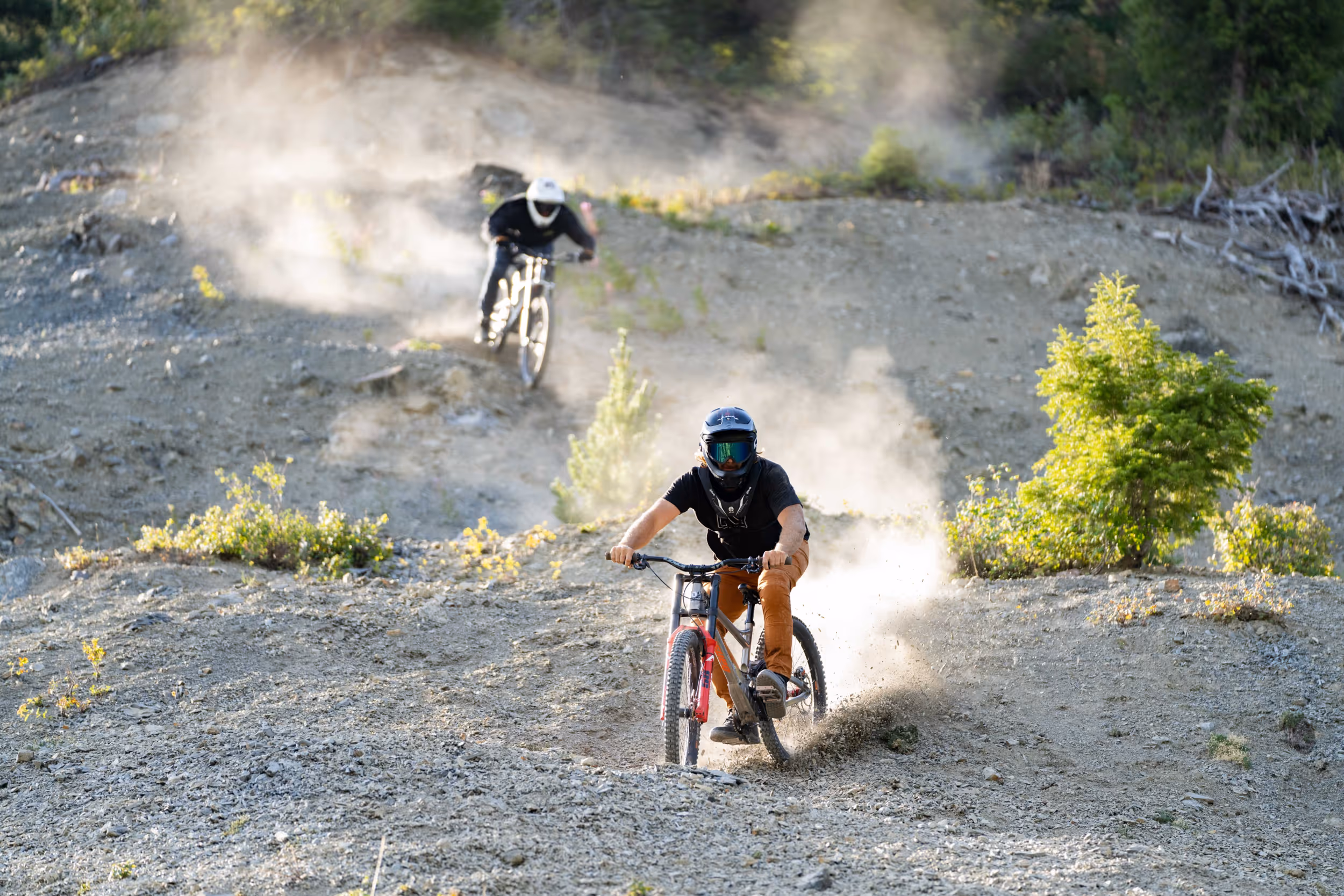 2 mountain bikers navigating their way down a dusty trail 