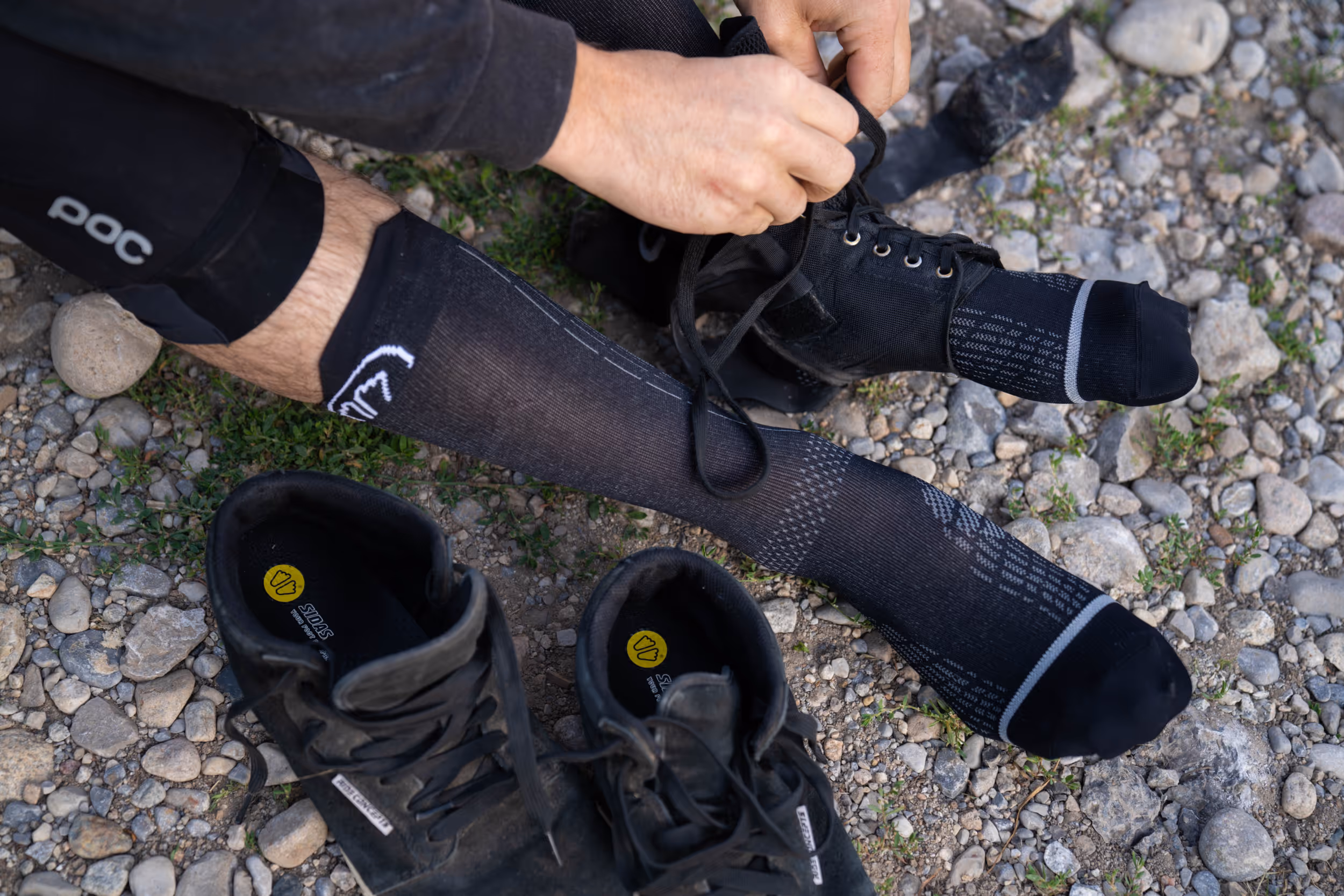 A mountain biker adjusting his ankle brace mid ride