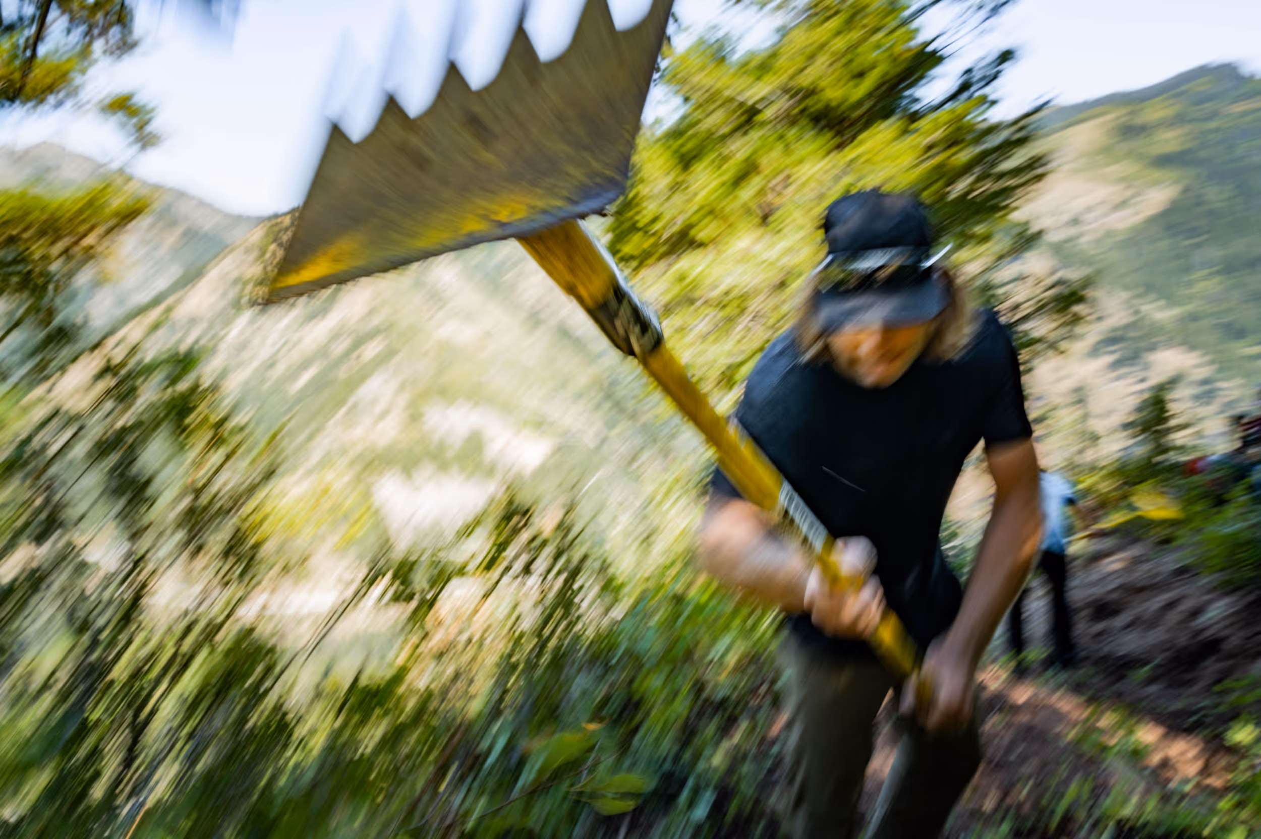 An action shot of a man performing some trail maintenance on a mountain bike trail 