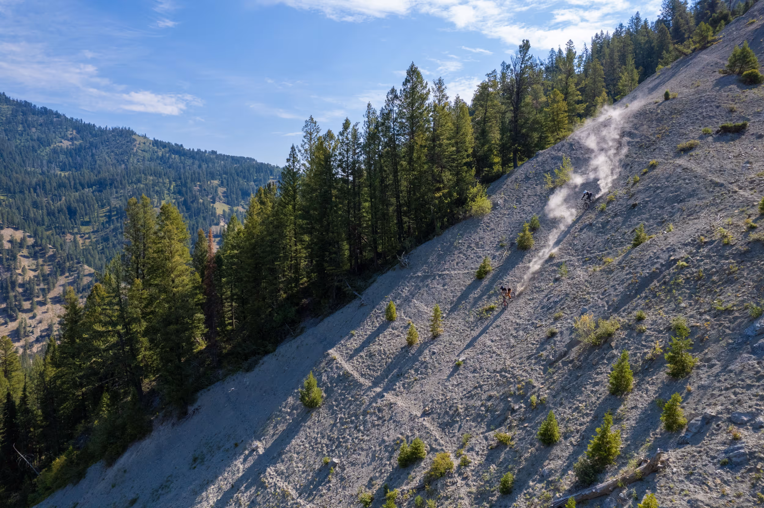 A far away view of a mountain biker navigating their way town a dusty, technical trail 