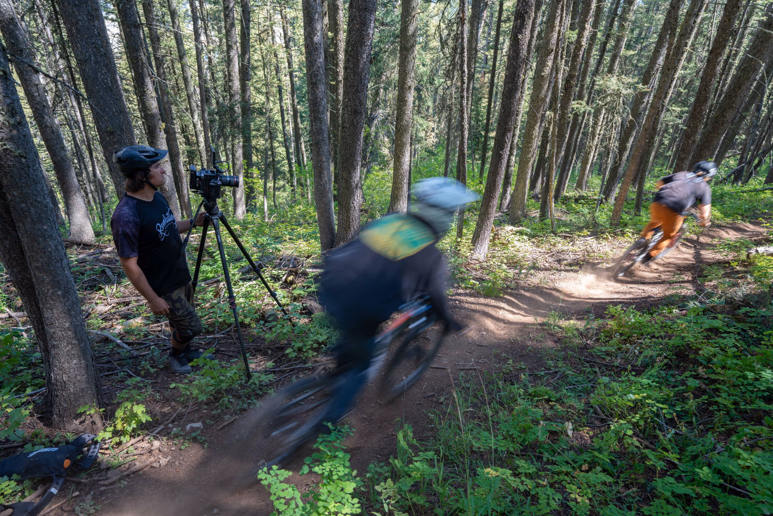 An action shot of 2 mountain biers ripping it through a forested trail 