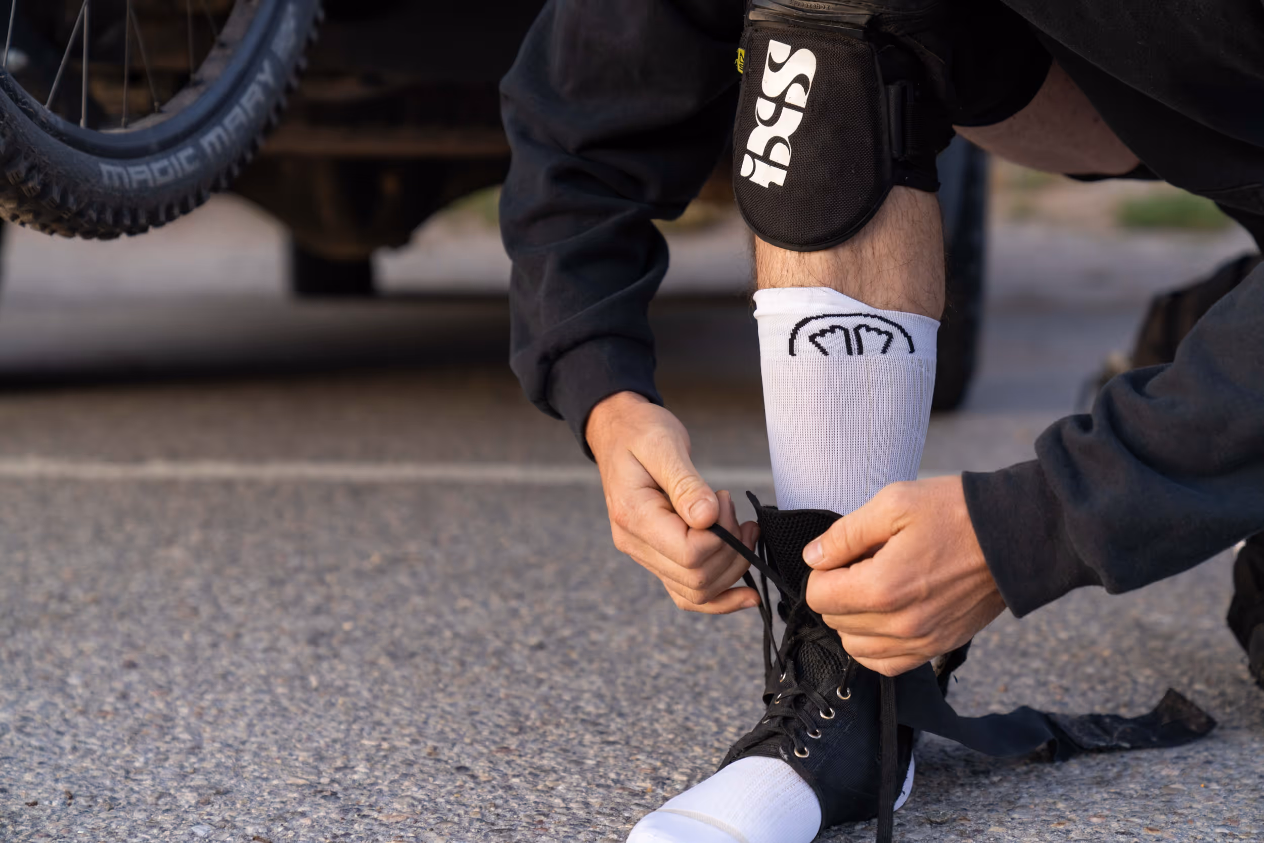 A mountain biker putting on an ankle brace in preparation for biking