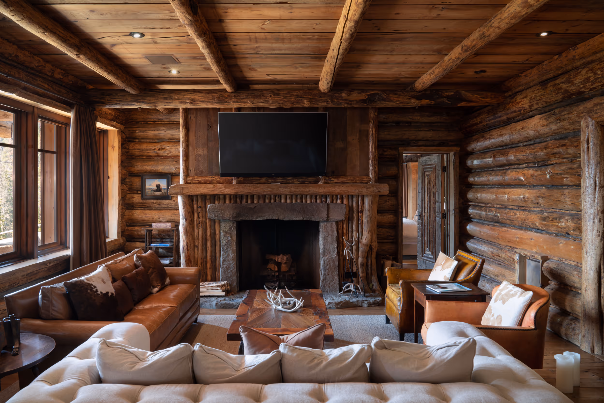 A large tv room over an impressive fire place and log cabin walls 
