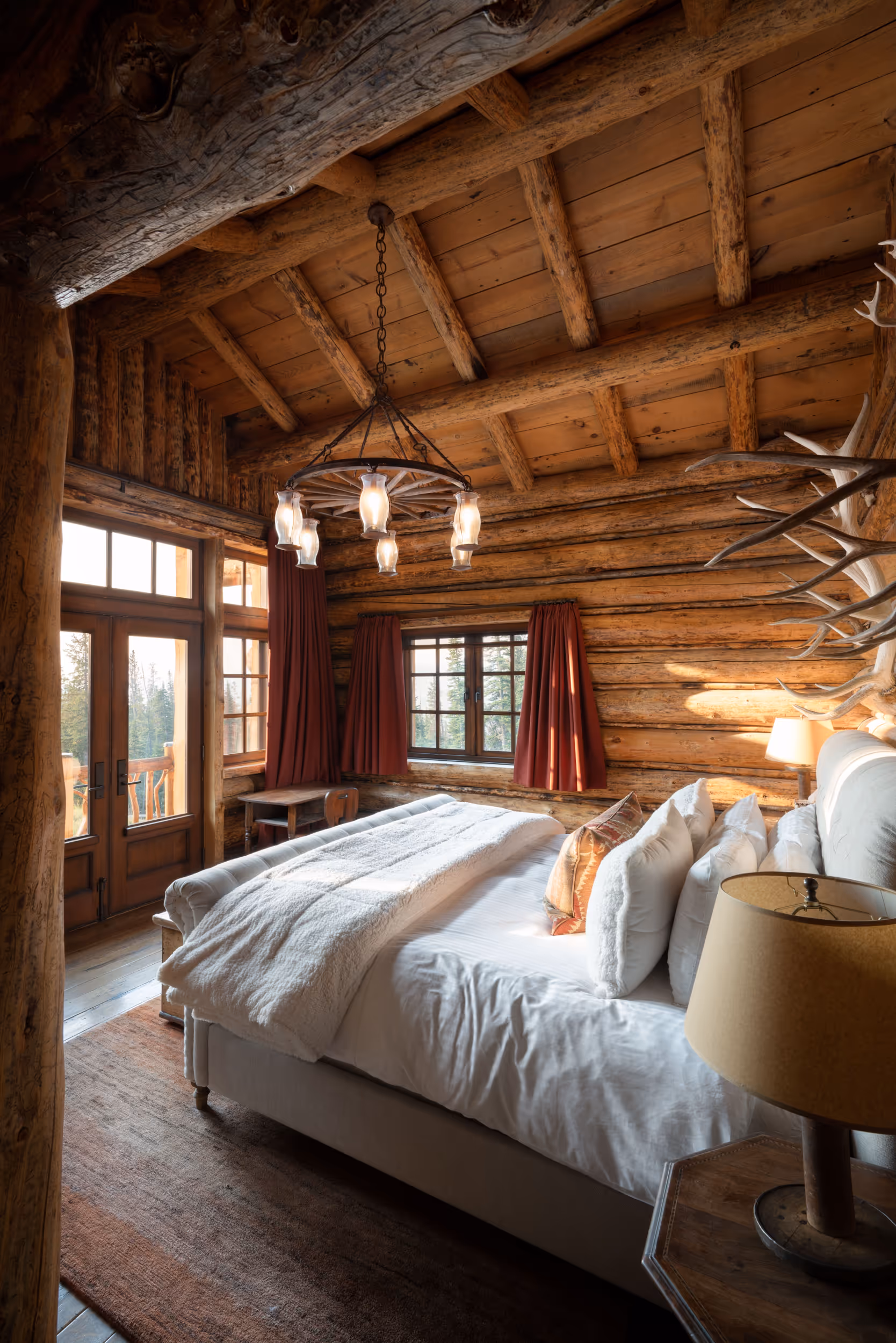 A large log cabin bedroom with a lovely plush bed and antler decorations 