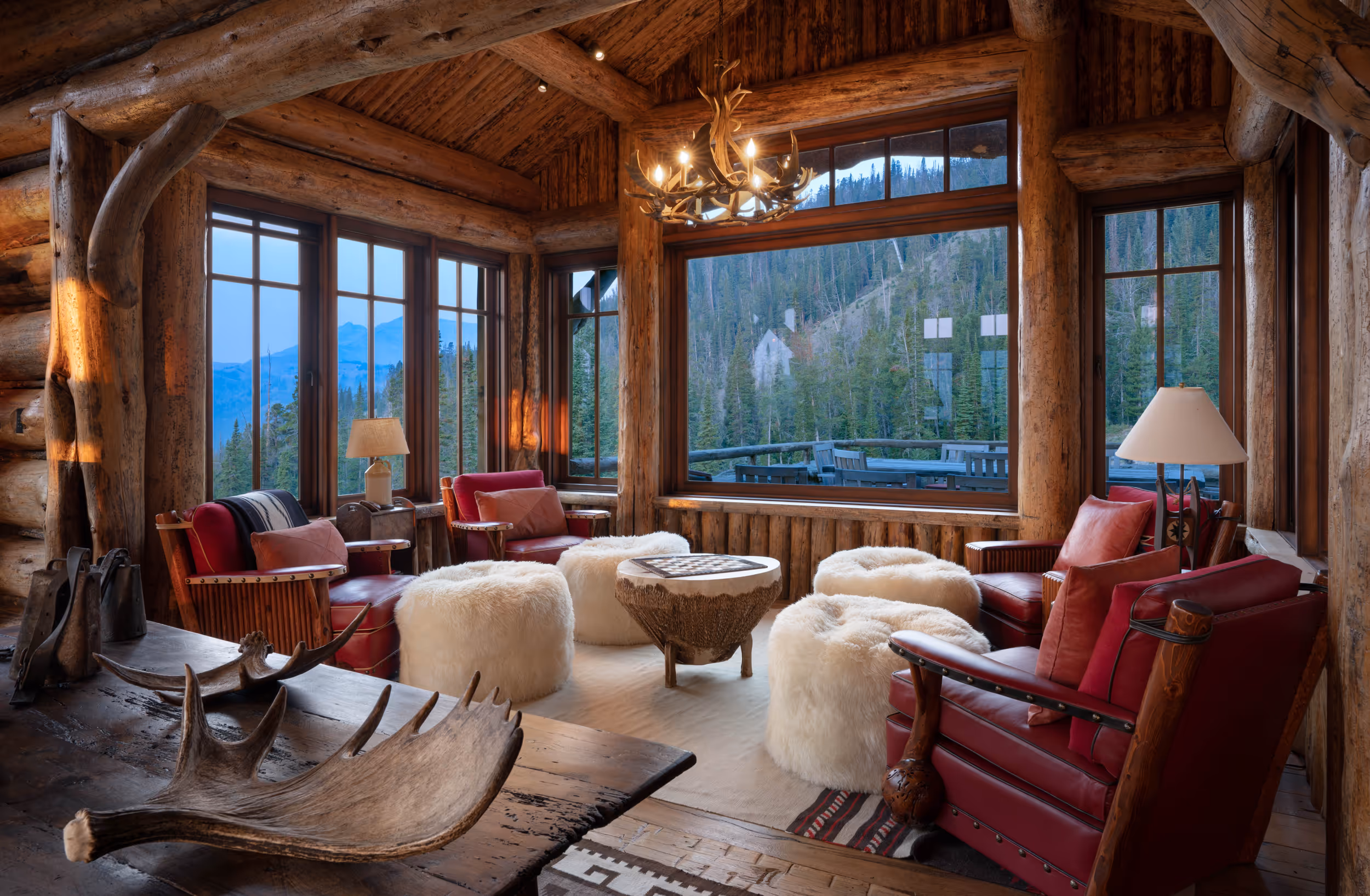 A luxury log cabin living area surrounded by large windows 