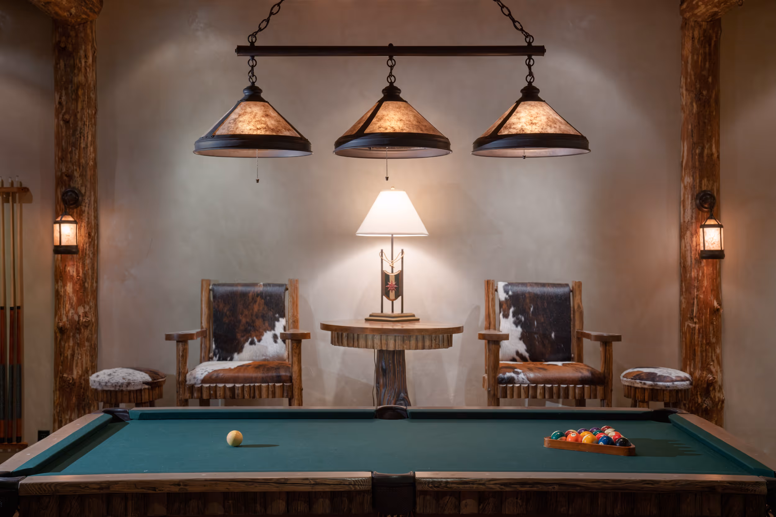 A well lit pool table on the inside of a luxurious log cabin 