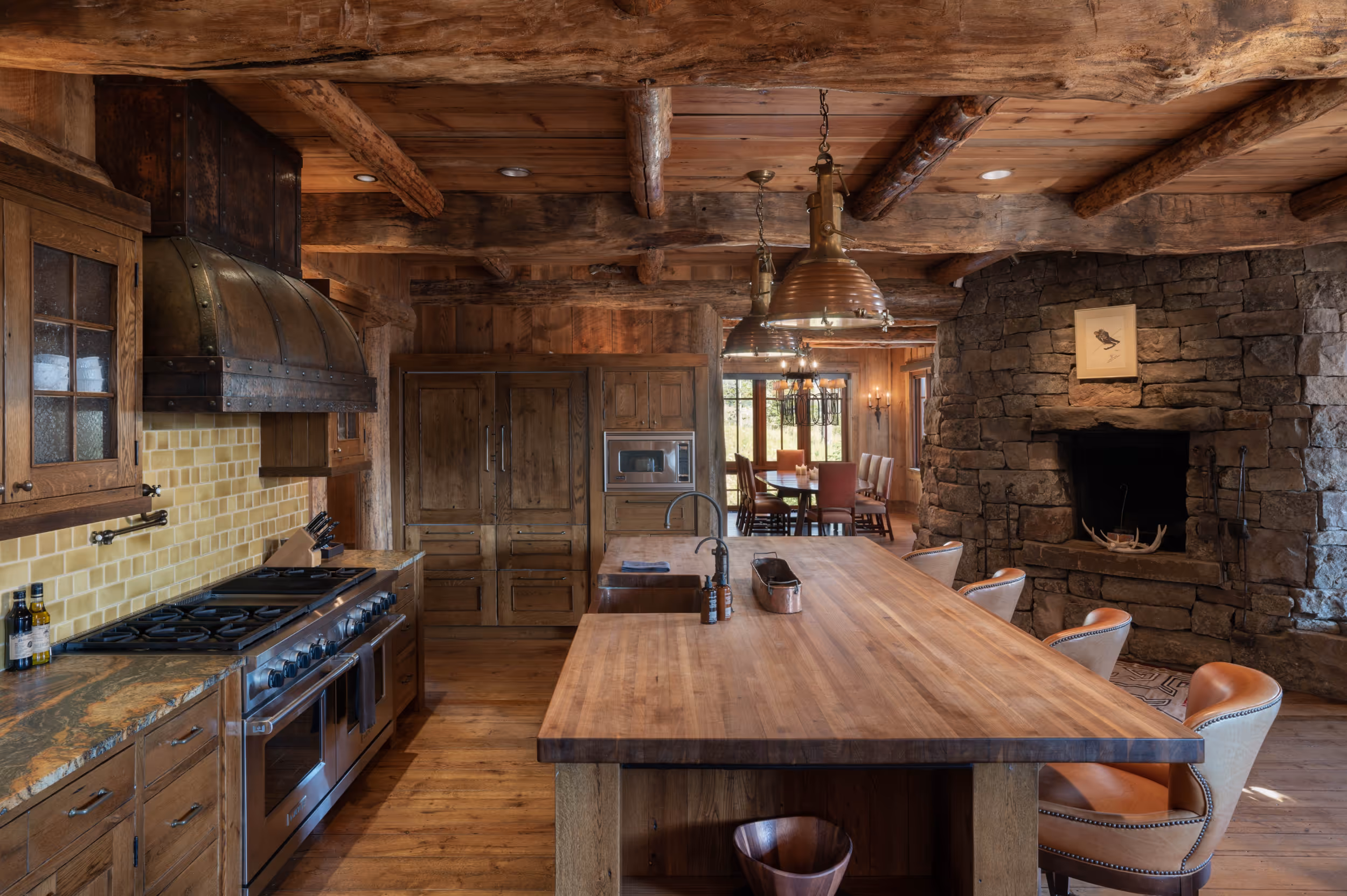 An overview of the kitchen area in a luxurious wooden cabin showing the  kitchen island with a large stove