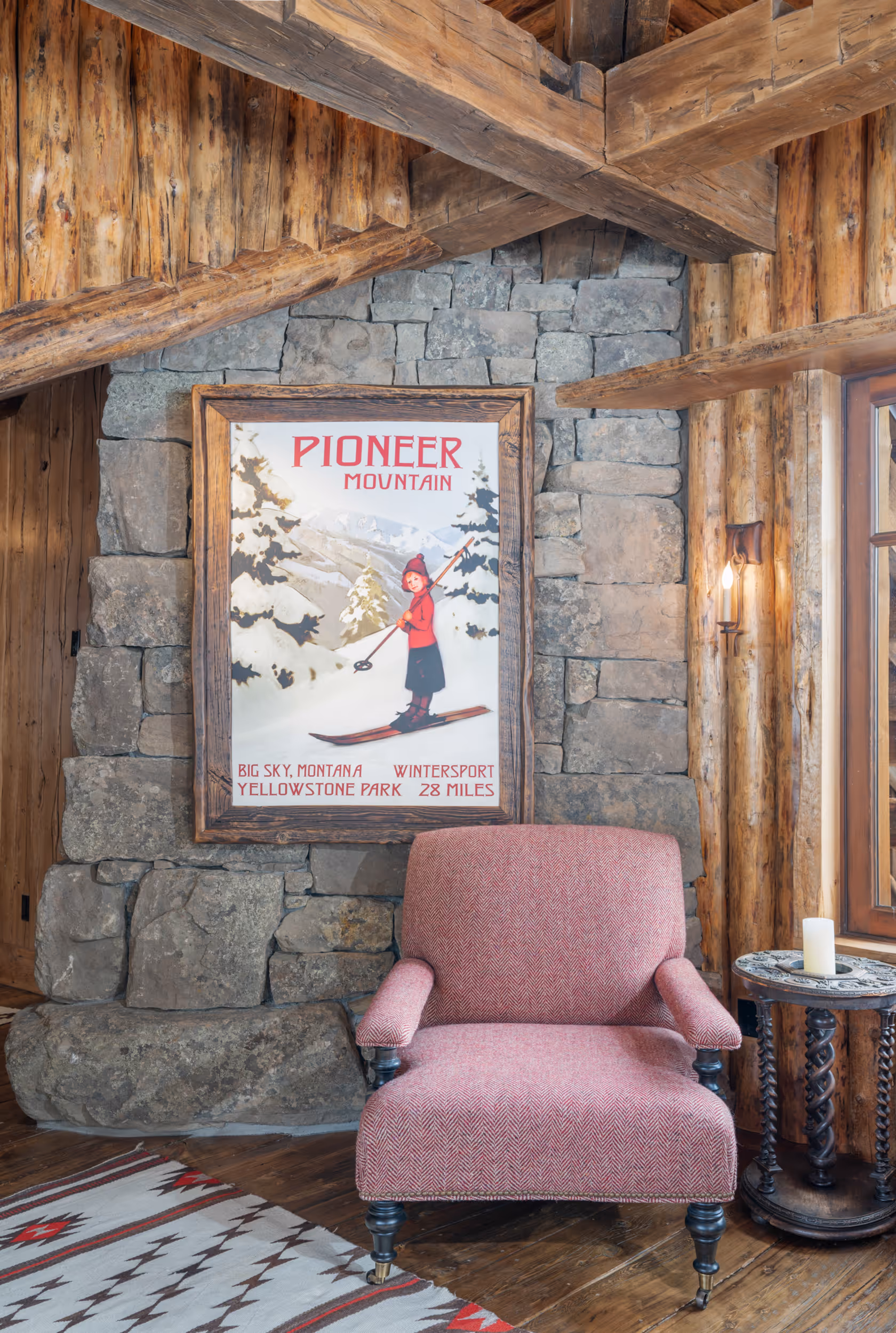 A cozy pink chair set against a stone wall on the inside of a luxury log cabin