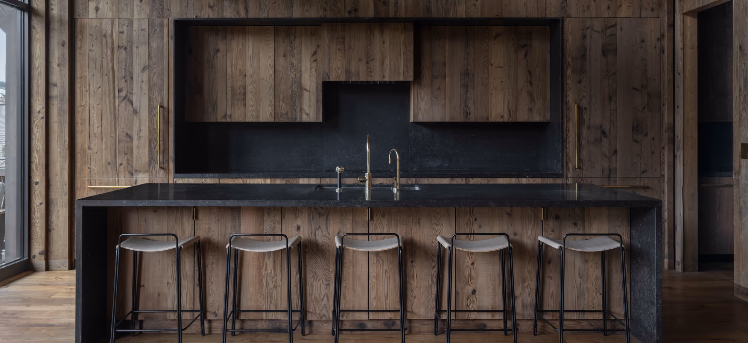A wooden kitchen with a dark, modern aesthetic 