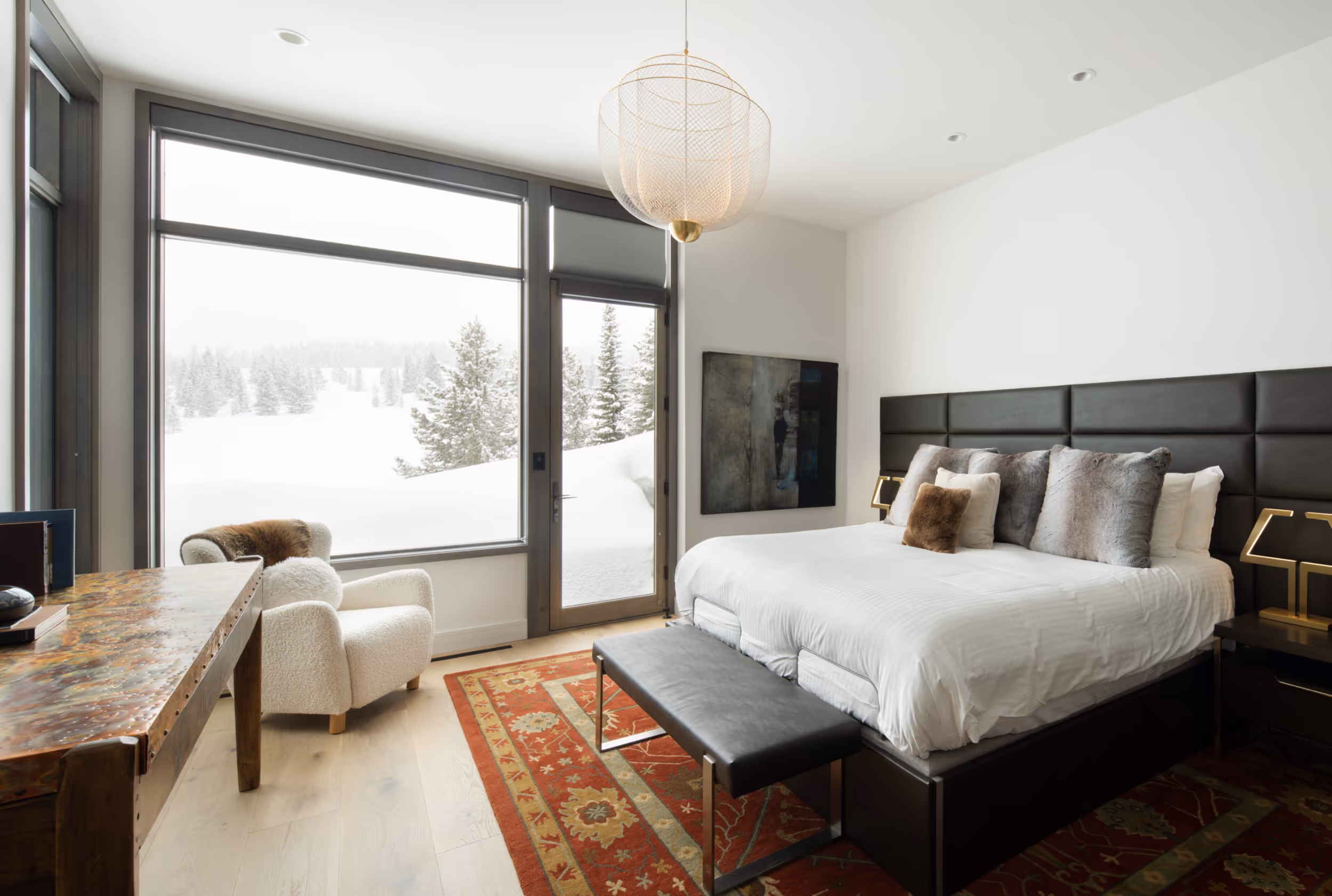 A spacious bedroom with a luxurious bed, and a wall that's made almost entirely of windows 