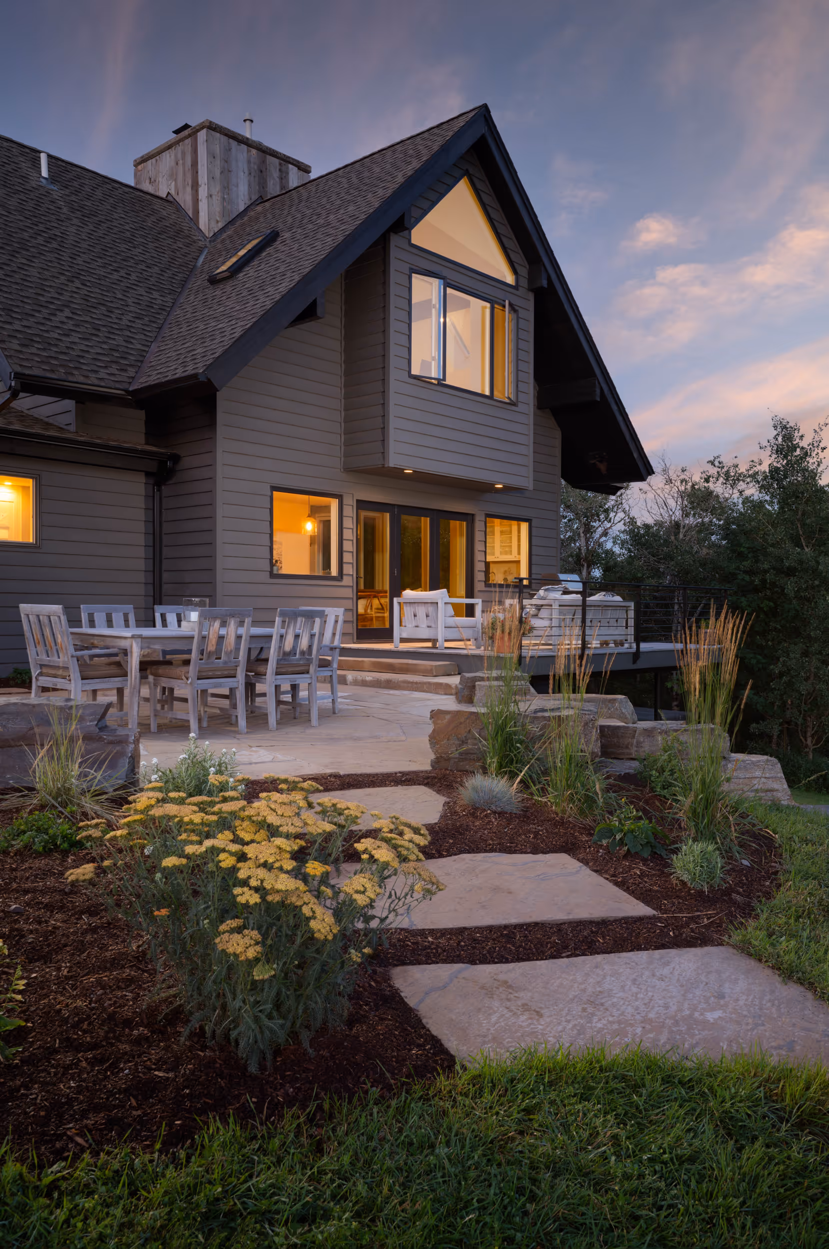 A stone path through a garden leading up to a patio in front of a house