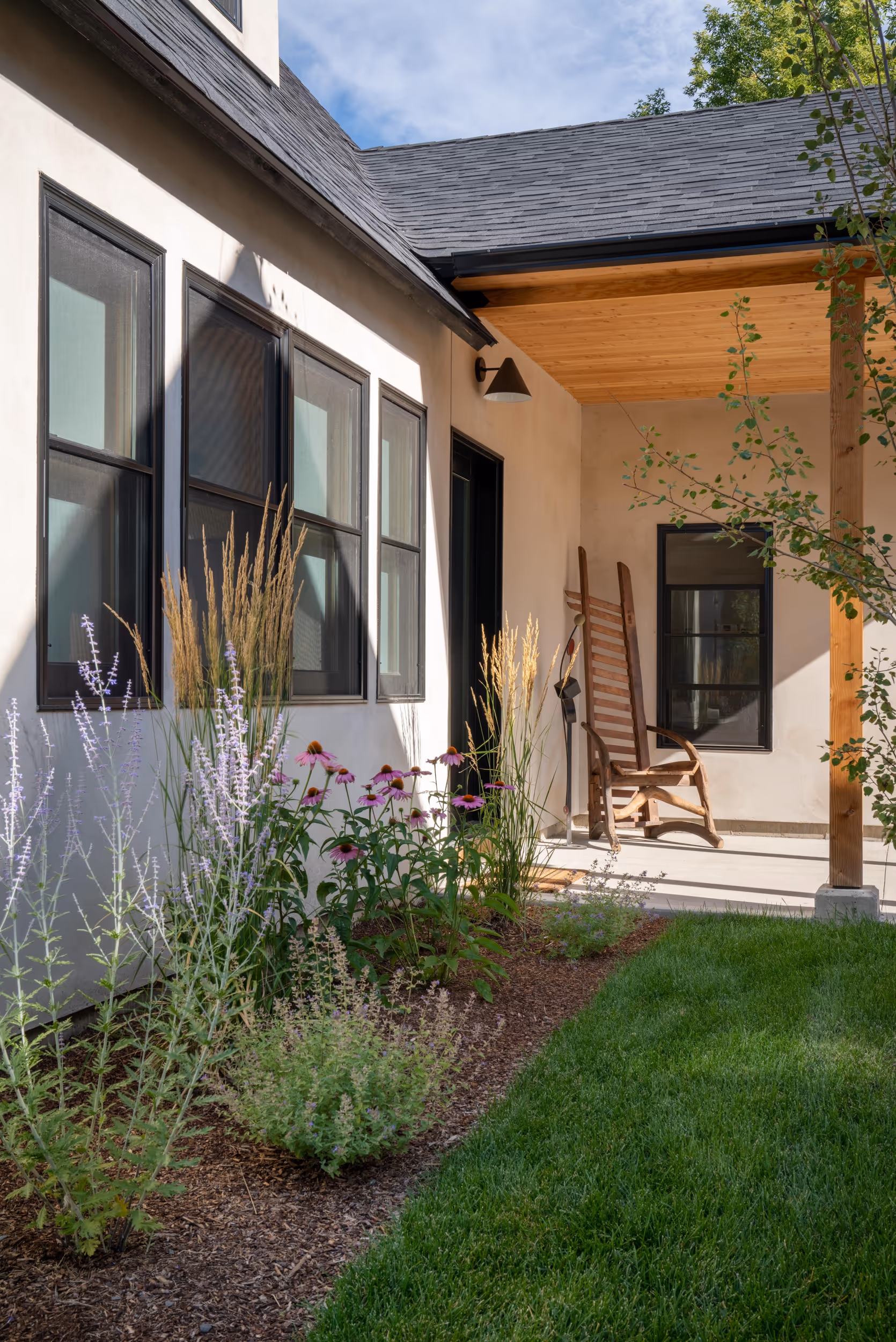 A flower garden next to the front of a house