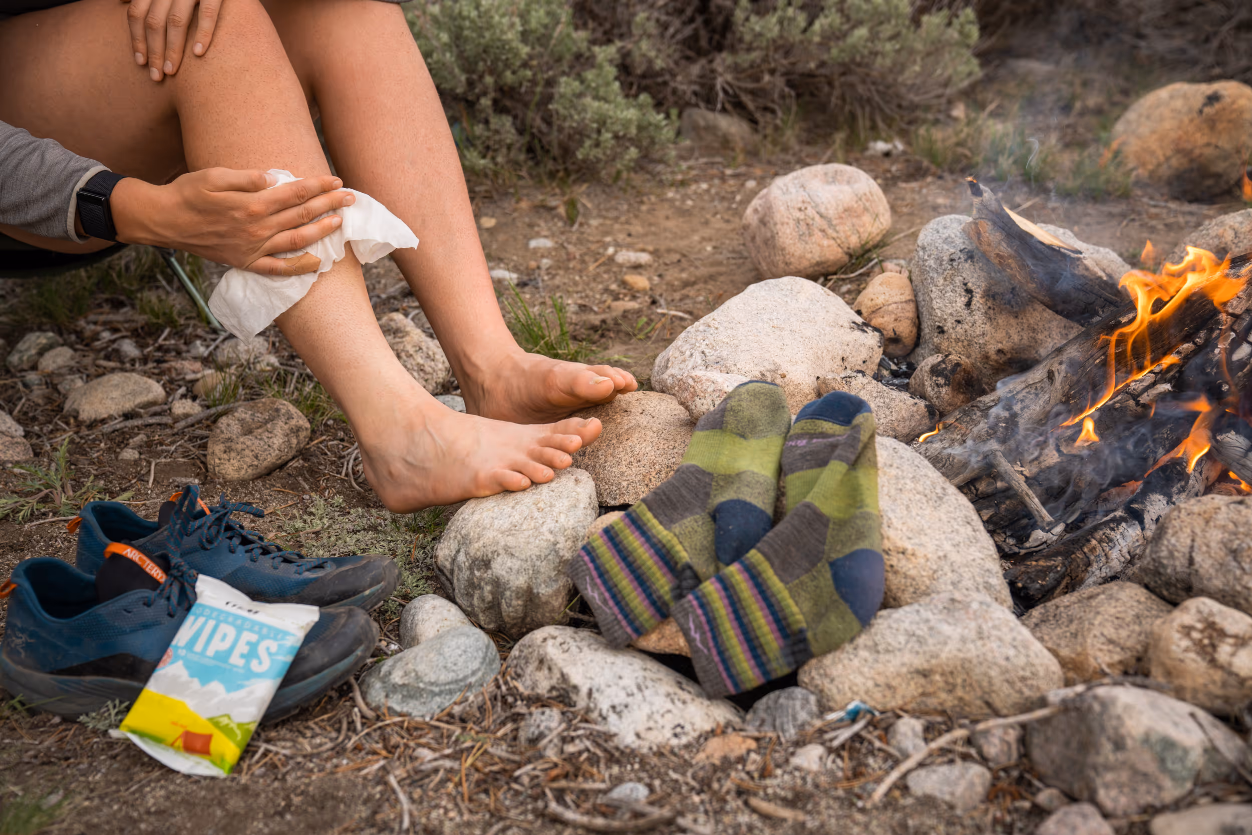 A camper using Bar-D body wipes around a campfire 