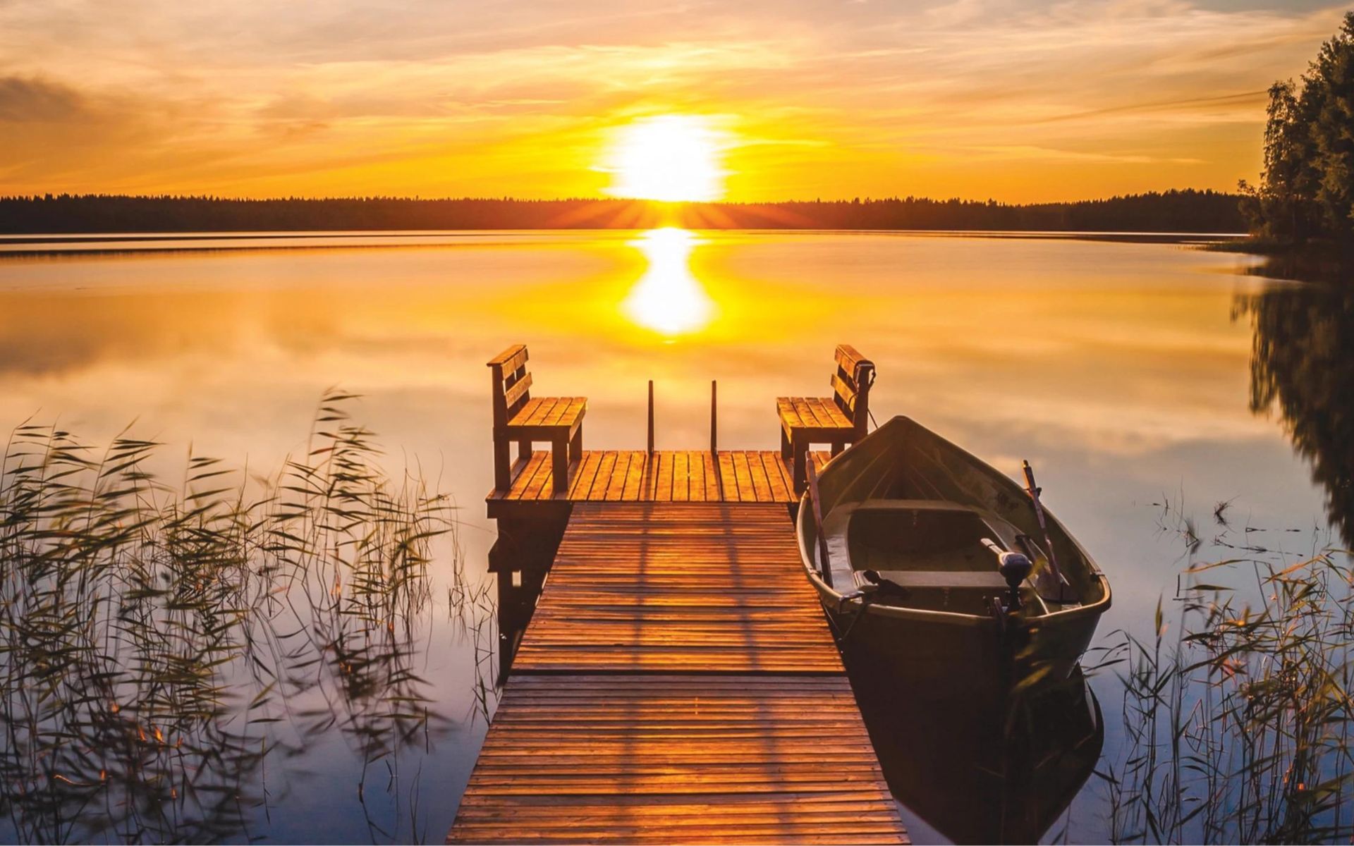 Sunset over the lake with a wooden dock and boat