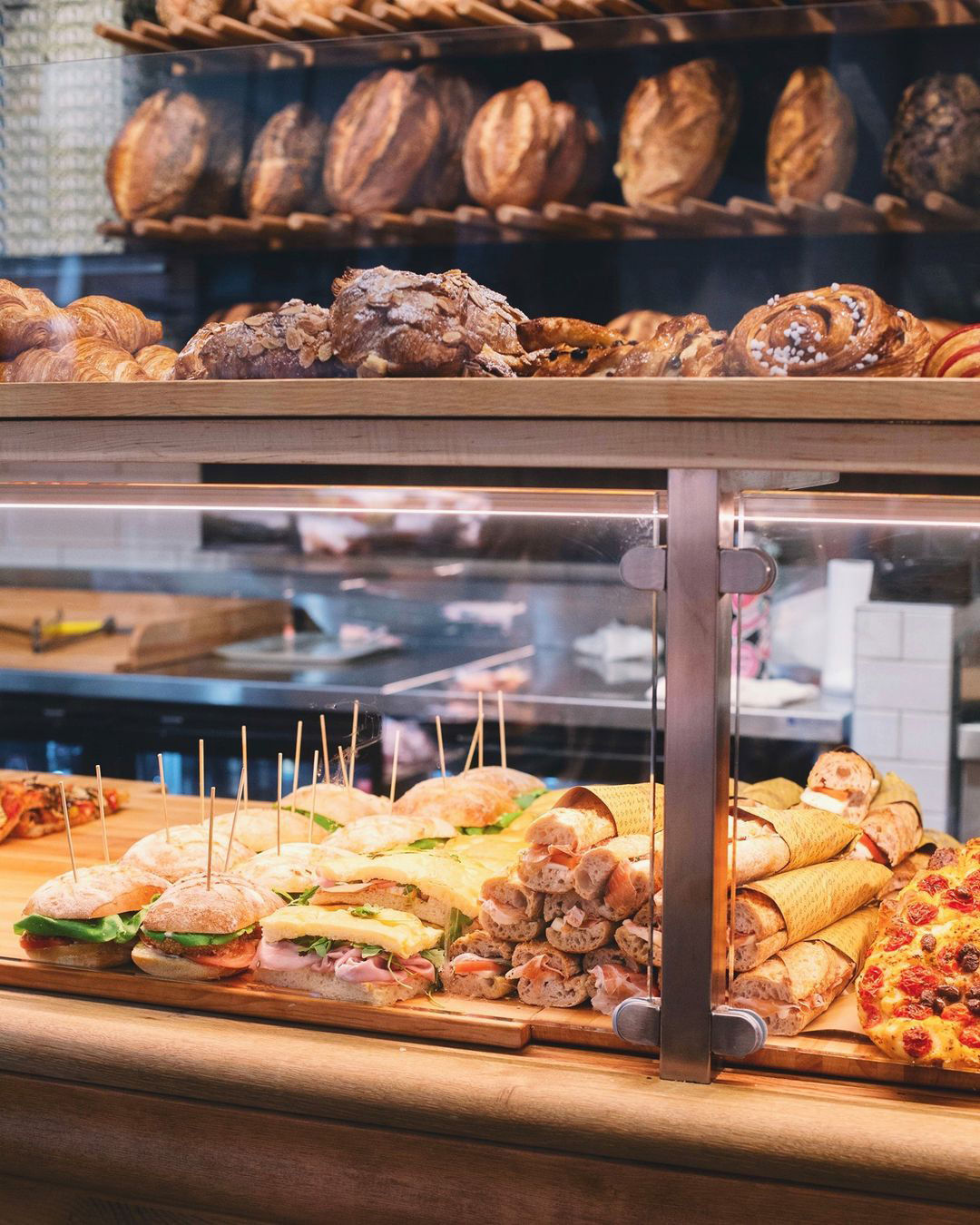 Bakery display case with fresh bread, croissants, and prepared sandwiches
