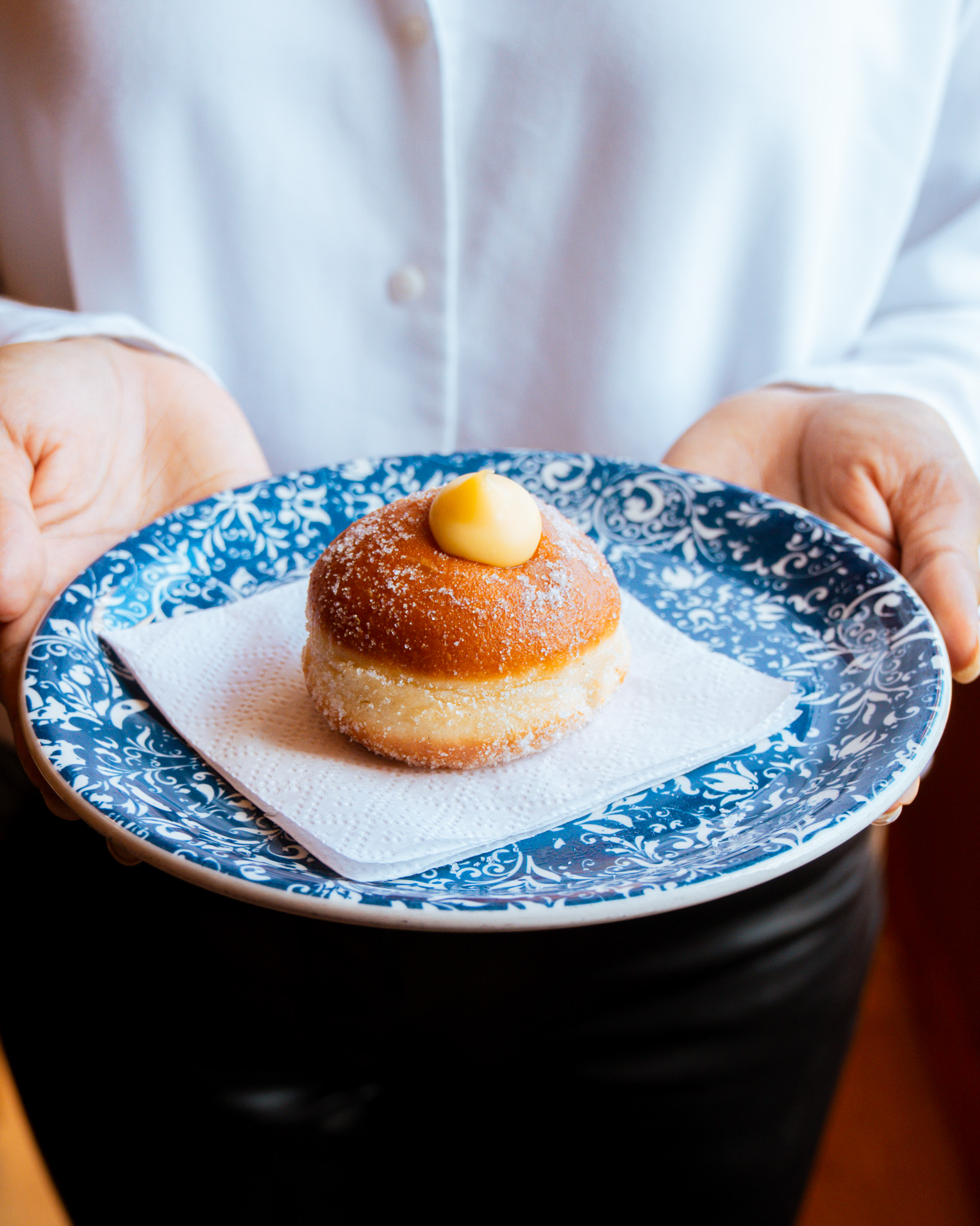 Server holding a plate with a cream-filled bombolini pastry