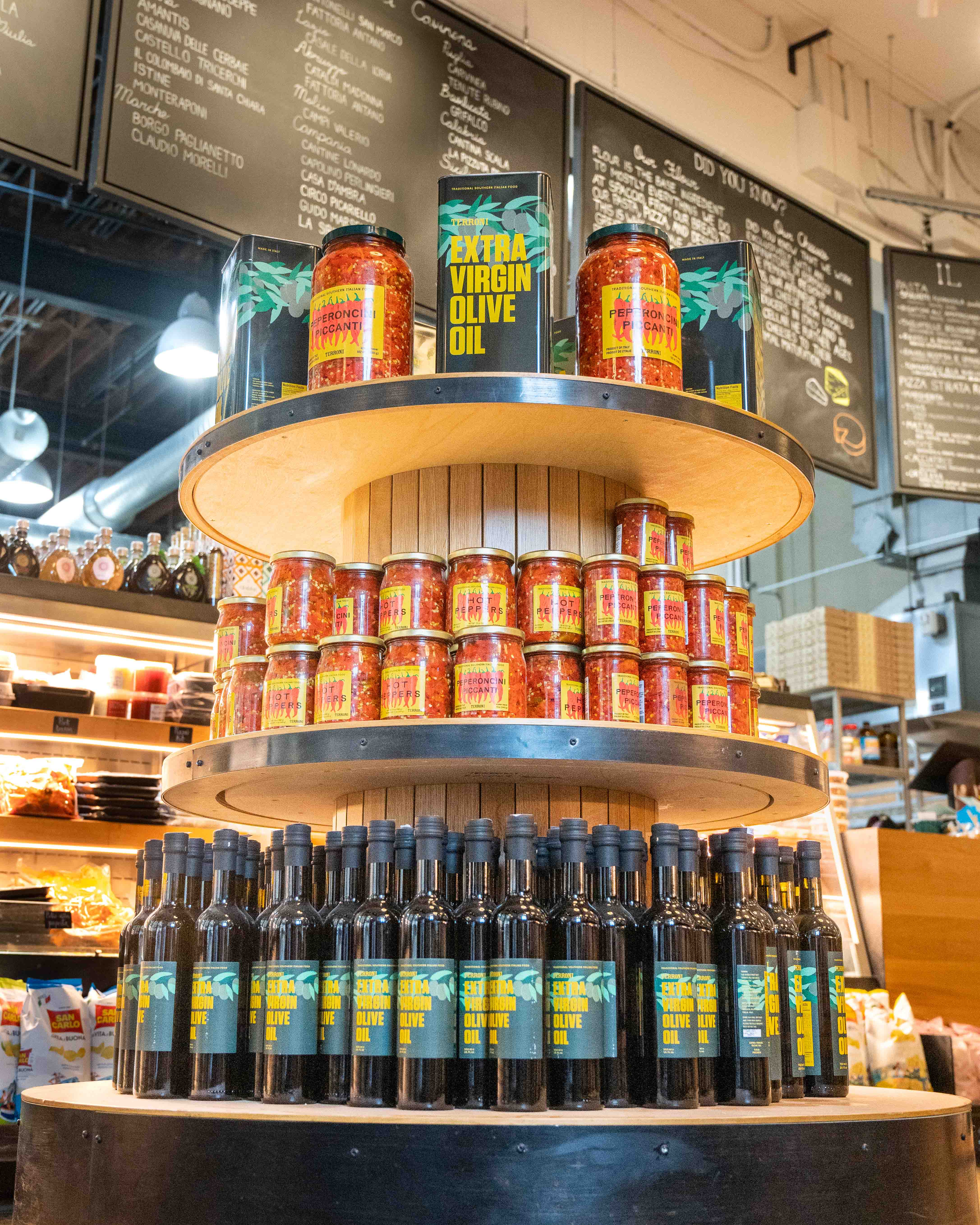 Tiered display stacked with jars of Terroni peperoncini piccanti and bottles of Terroni olive oil