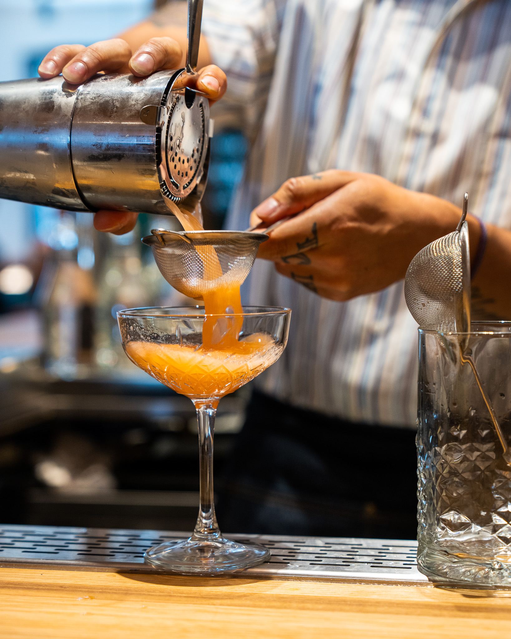 Bartender straining a cocktail into a coupe glass at Terroni Sterling