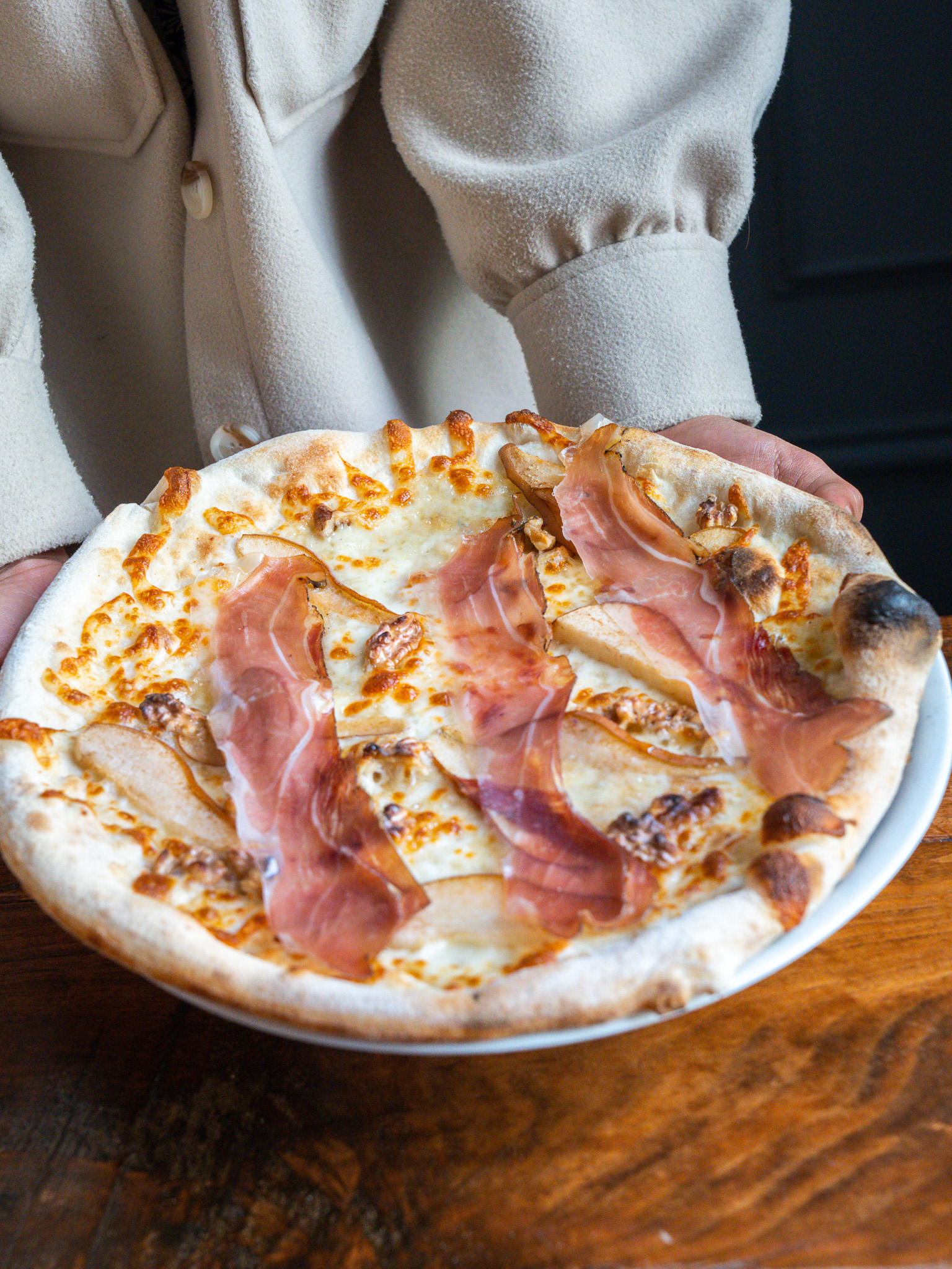 Server presenting a prosciutto and pear pizza at Terroni Sterling
