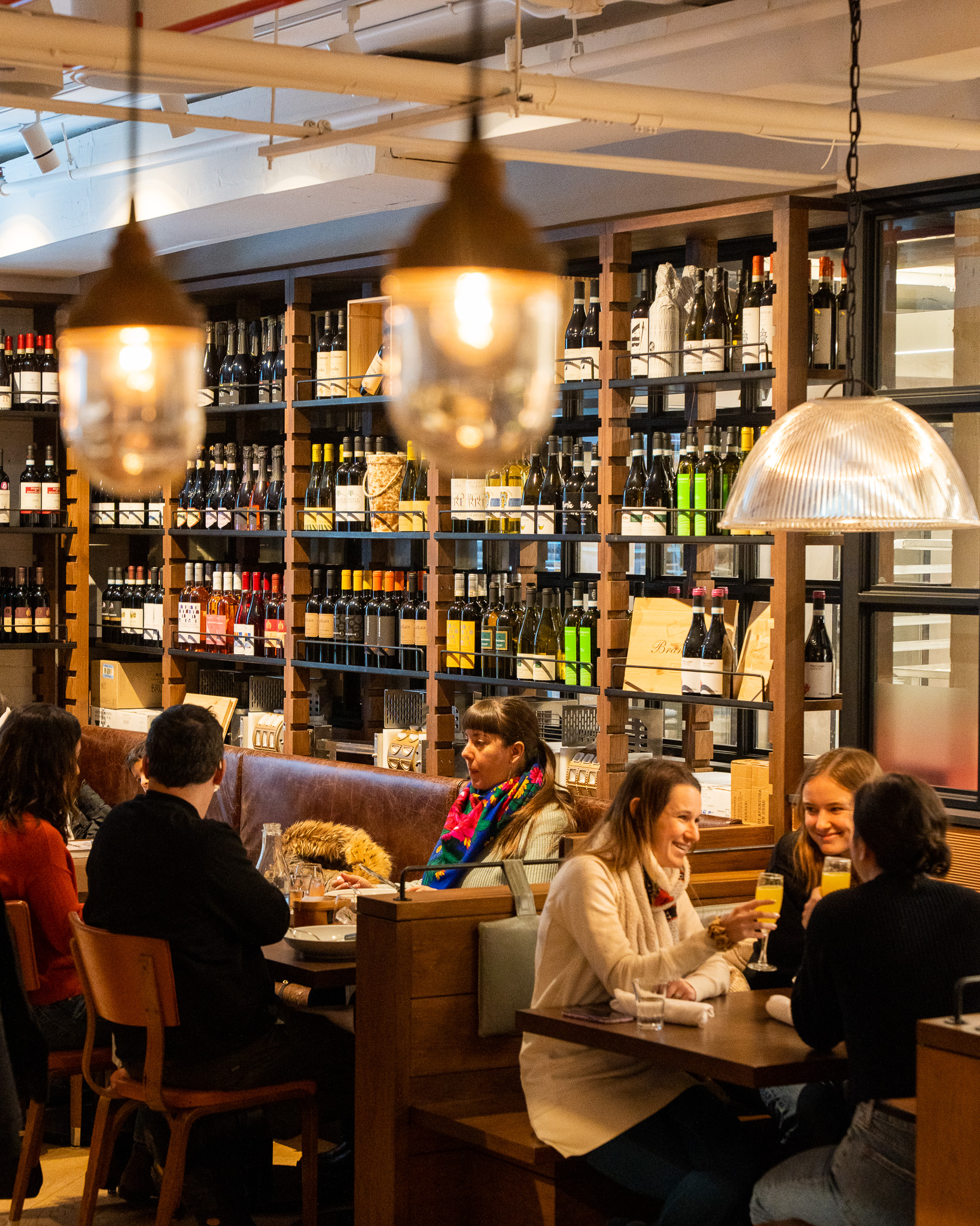 Friends toasting wine glasses at a table beside the wine shelves at Terroni Sterling