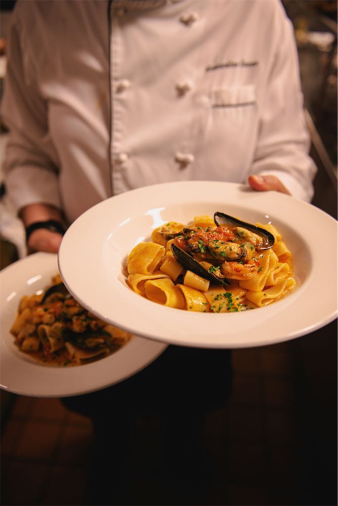 Chef holding a bowl of pasta with mussels and shrimp