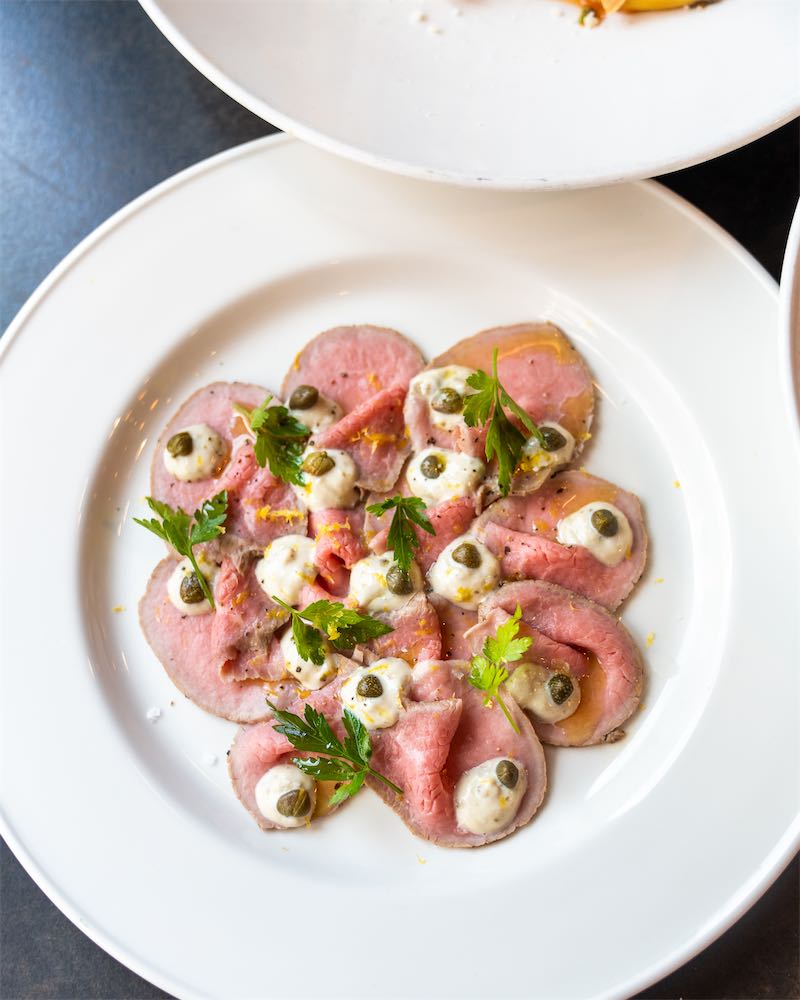 Overhead view of beef carpaccio with capers, parsley, and lemon zest