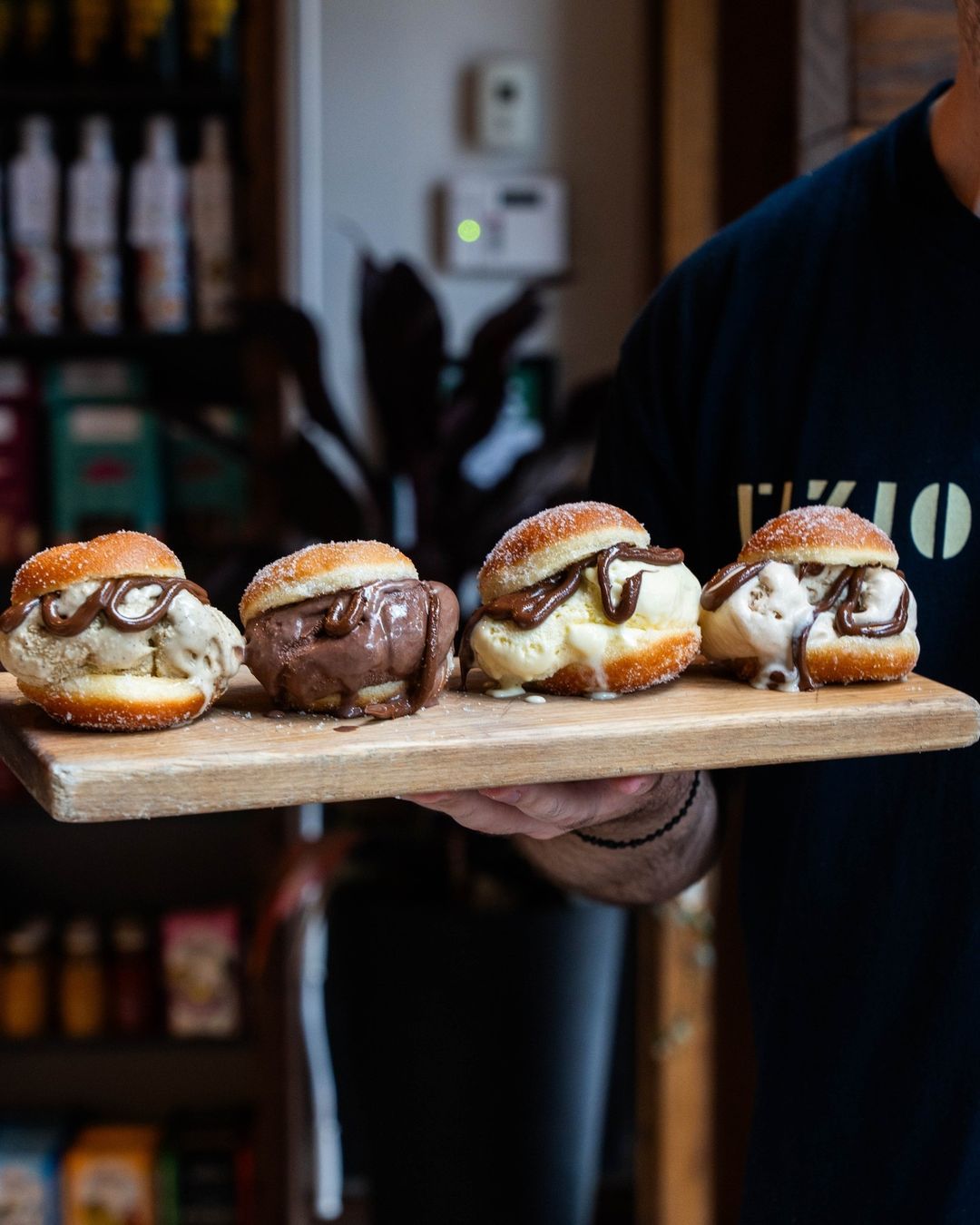 Ice cream-stuffed brioche buns drizzled with chocolate on a wood board