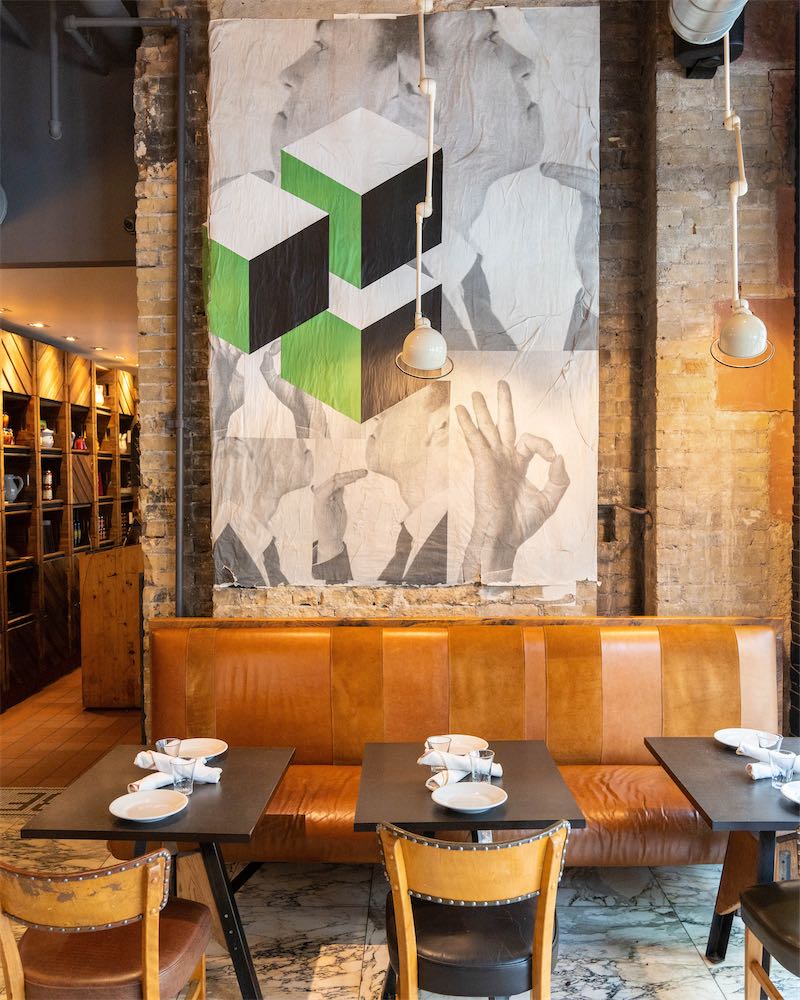 Dining room booth beneath a collage mural of hands and faces