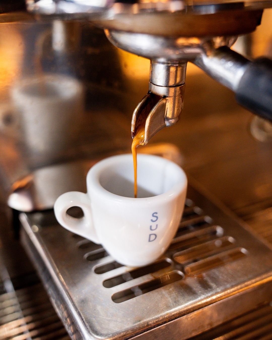 Espresso shot pulling into a cup stamped SUD