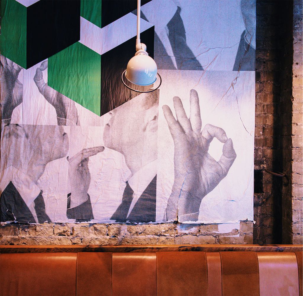 Close-up of the mural's hand gestures beneath a pendant lamp
