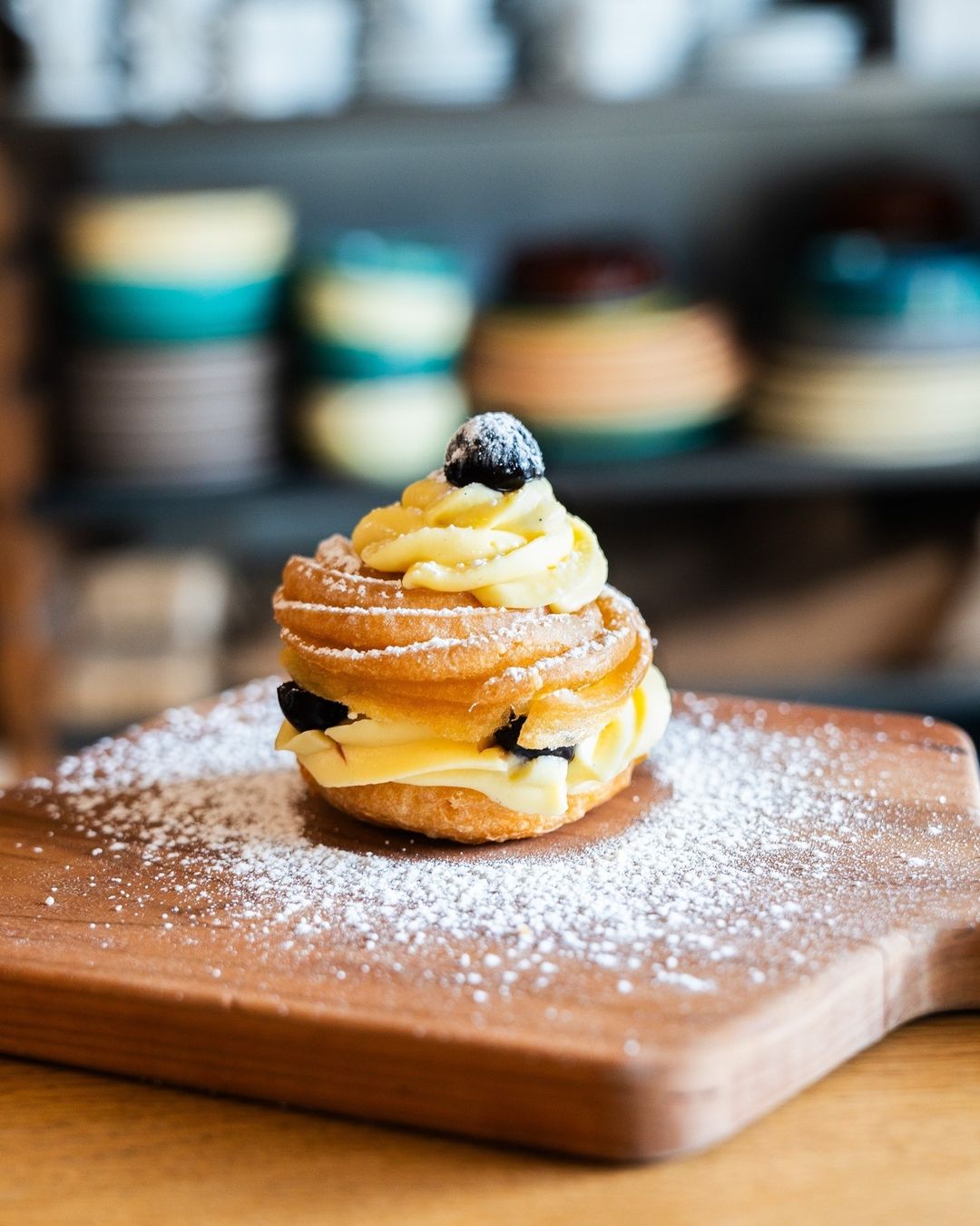 Cream-filled zeppola pastry dusted with powdered sugar on a wood board