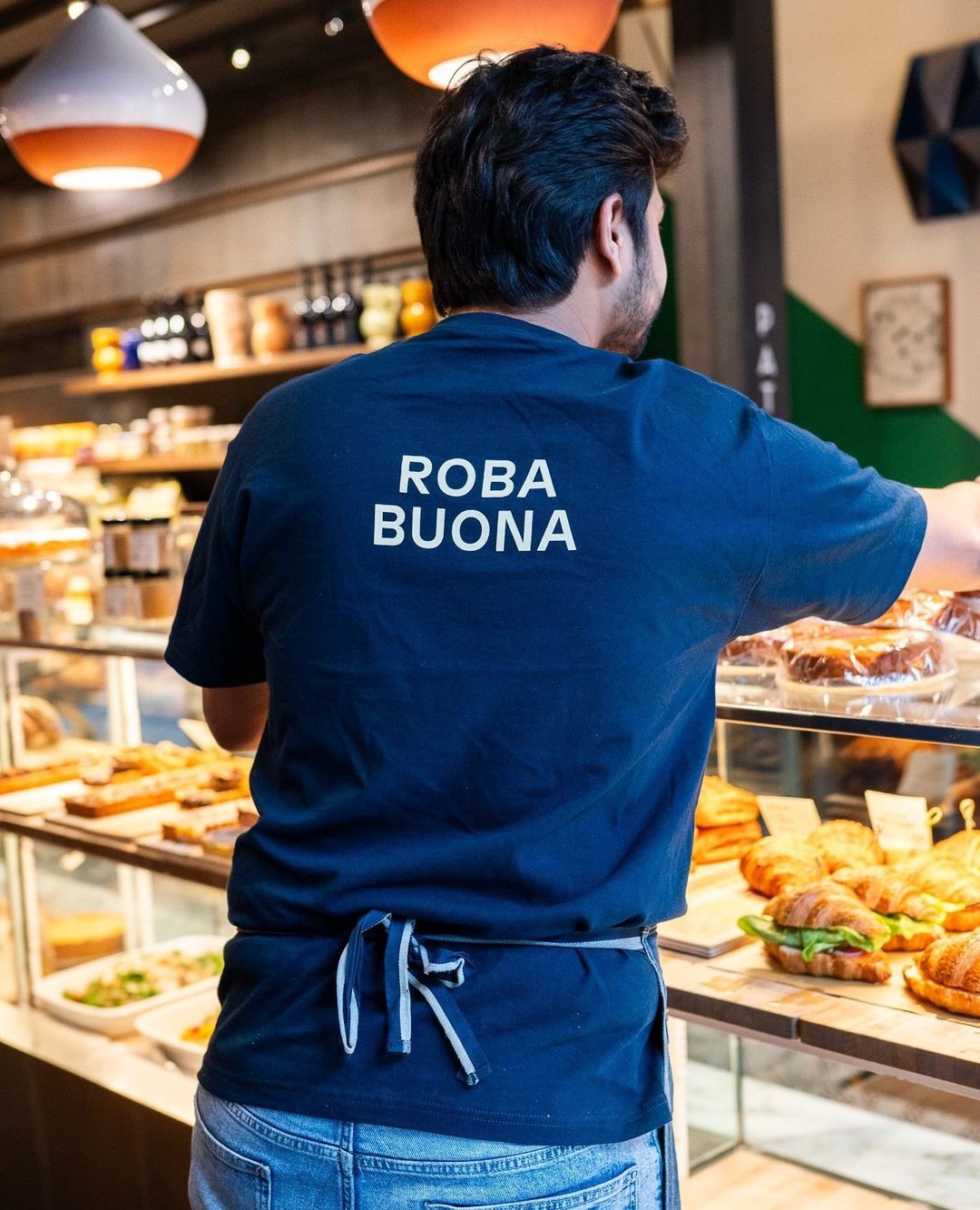 Server in a Roba Buona t-shirt reaching into the pastry display case