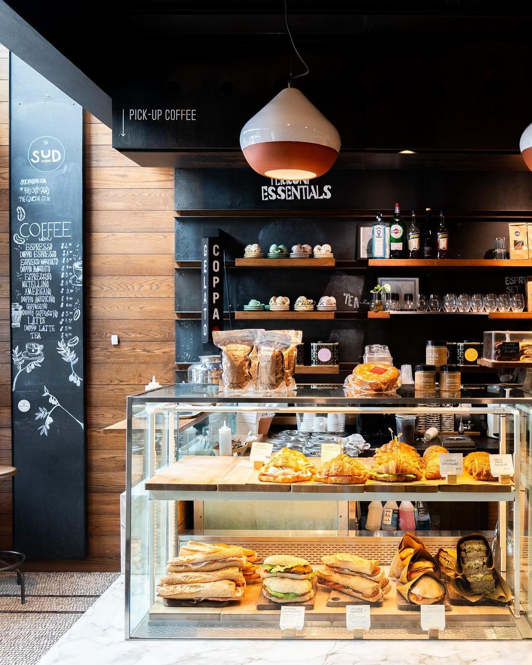 Bakery counter with bread shelves, pastry case, and a chalkboard coffee menu