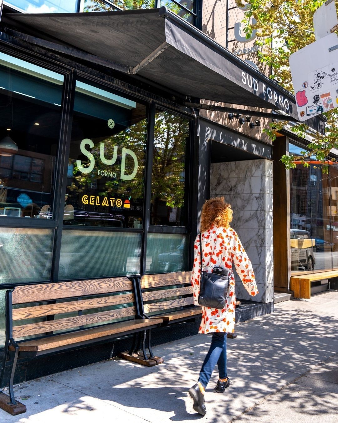 Woman walking past the Sud Forno storefront window and gelato sign