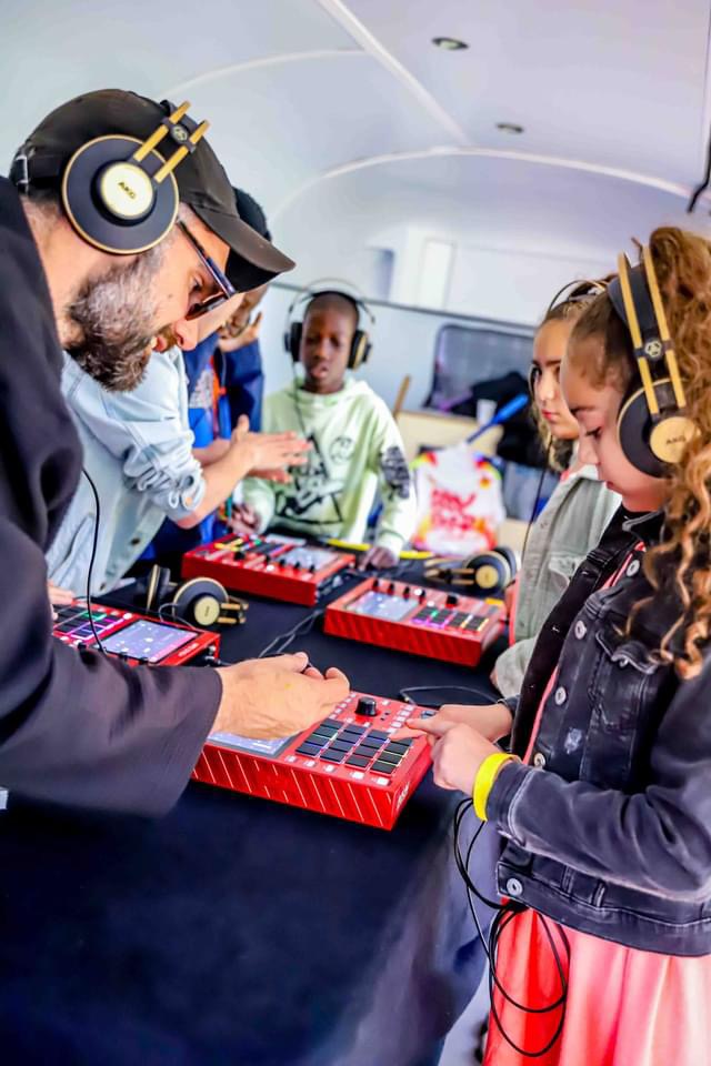 Atelier beatmaking : enfants au casque sur des pads avec un animateur