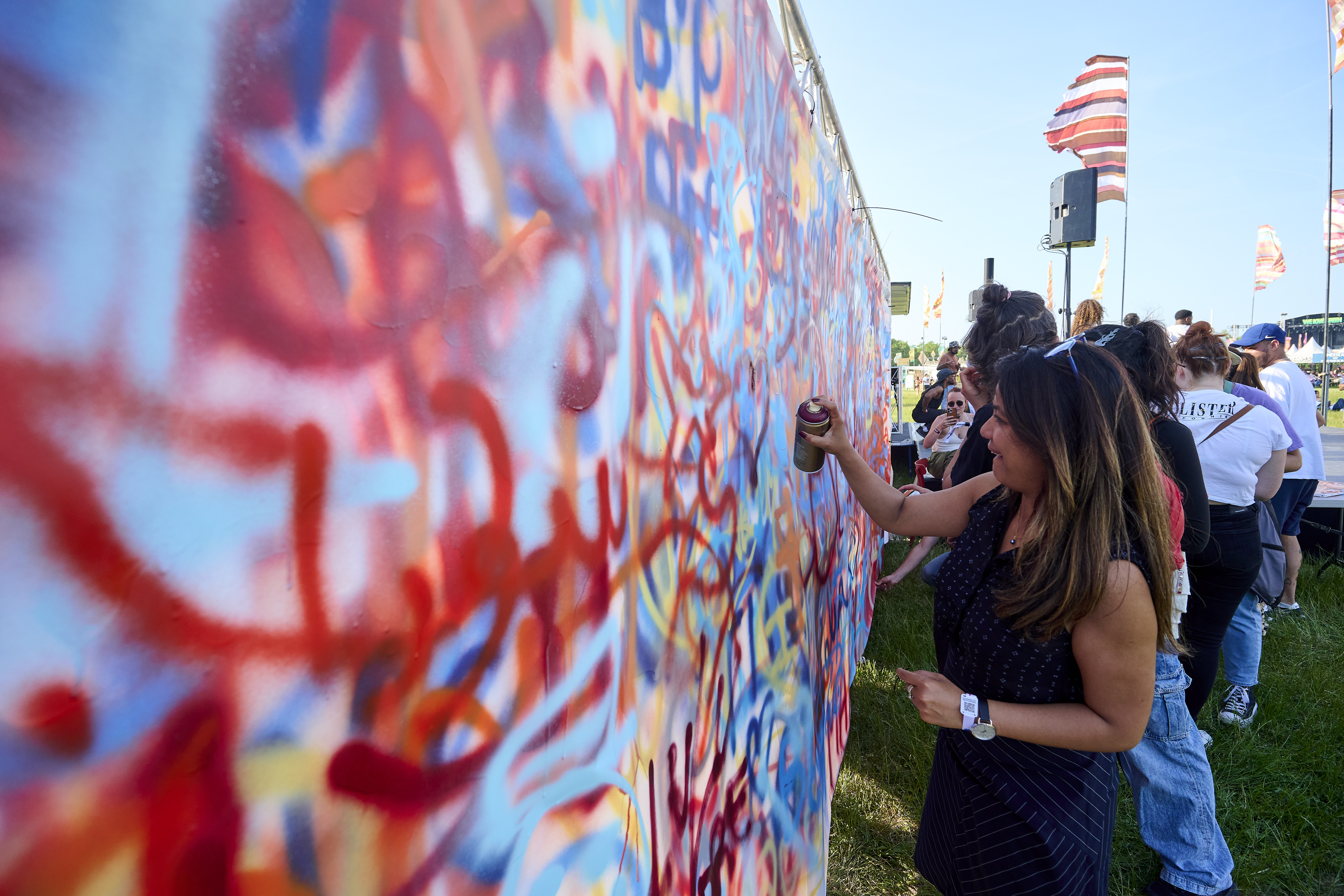 Atelier de street-art : participante qui peint une fresque à la bombe en plein air
