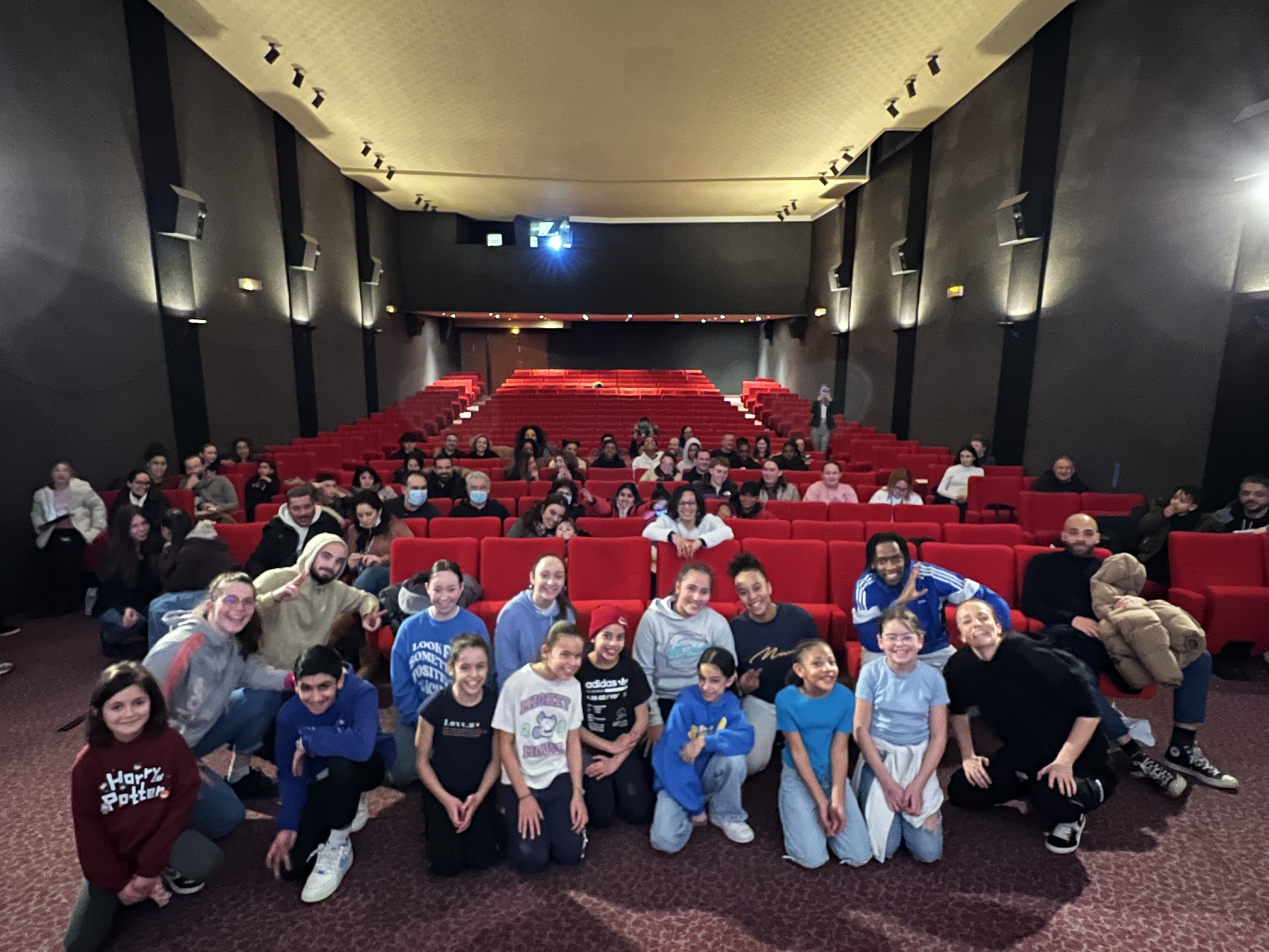 Photo de groupe des danseurs et du public dans la salle de cinéma après la performance hip-hop