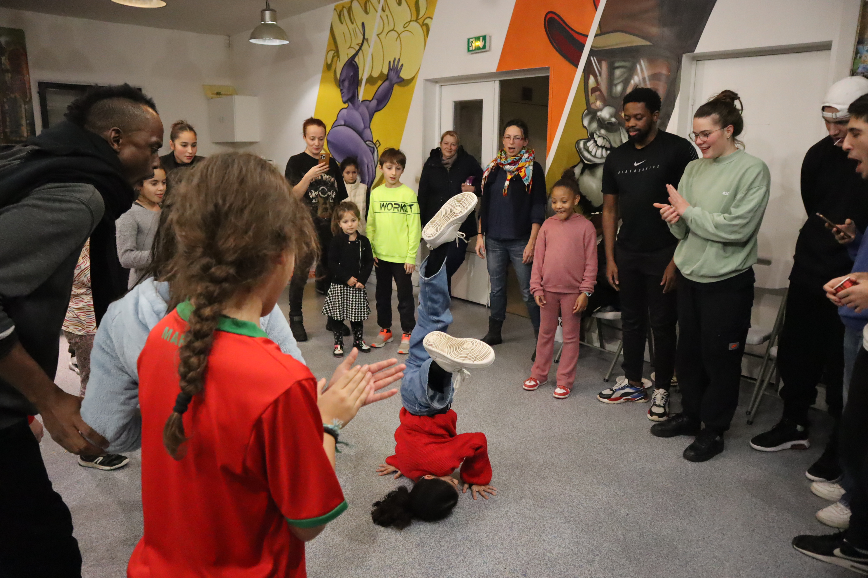 Cercle de danse : enfants et adultes encouragent un jeune breakeur