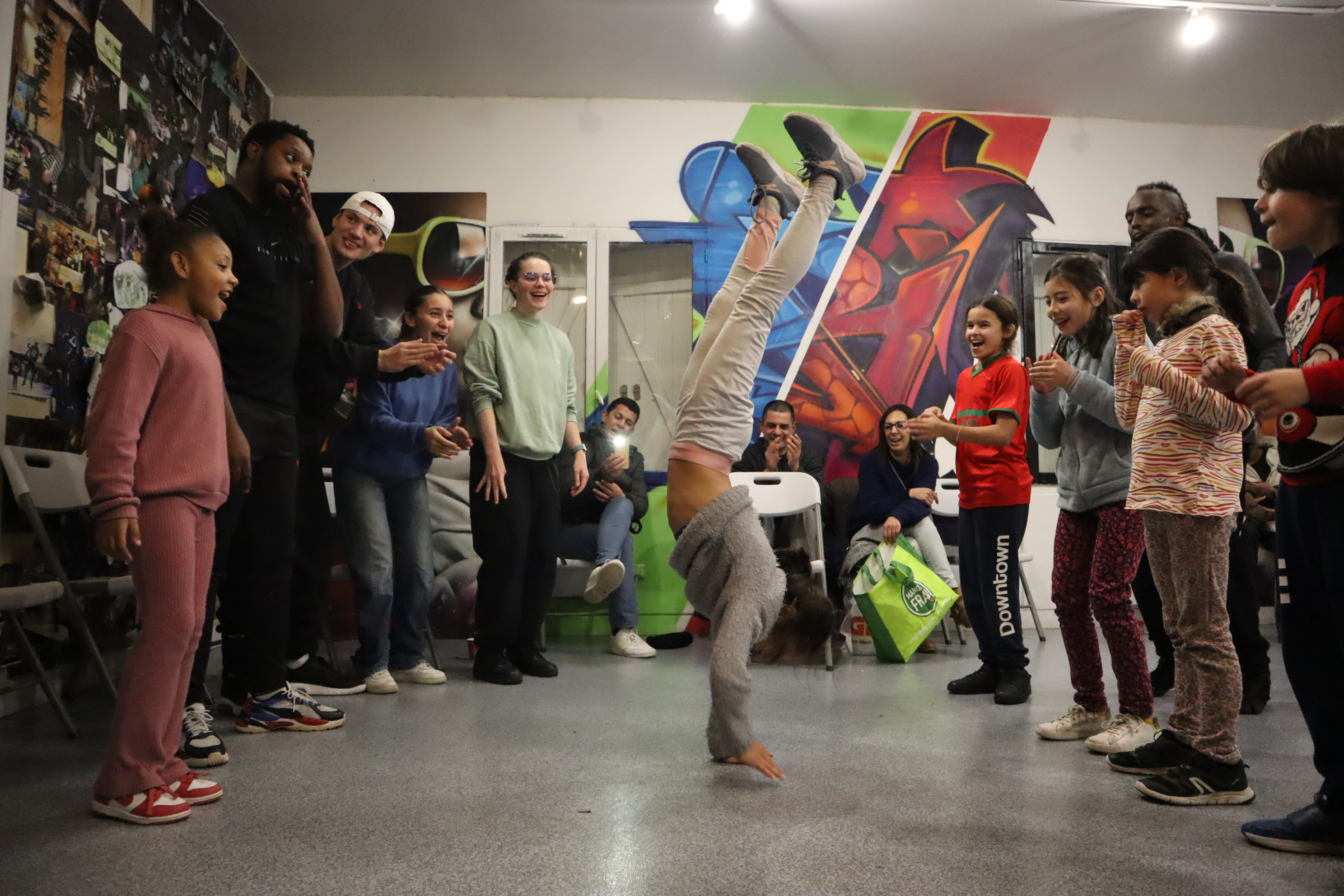 Enfant réalisant une figure de breaking au centre d'un cercle de danseurs