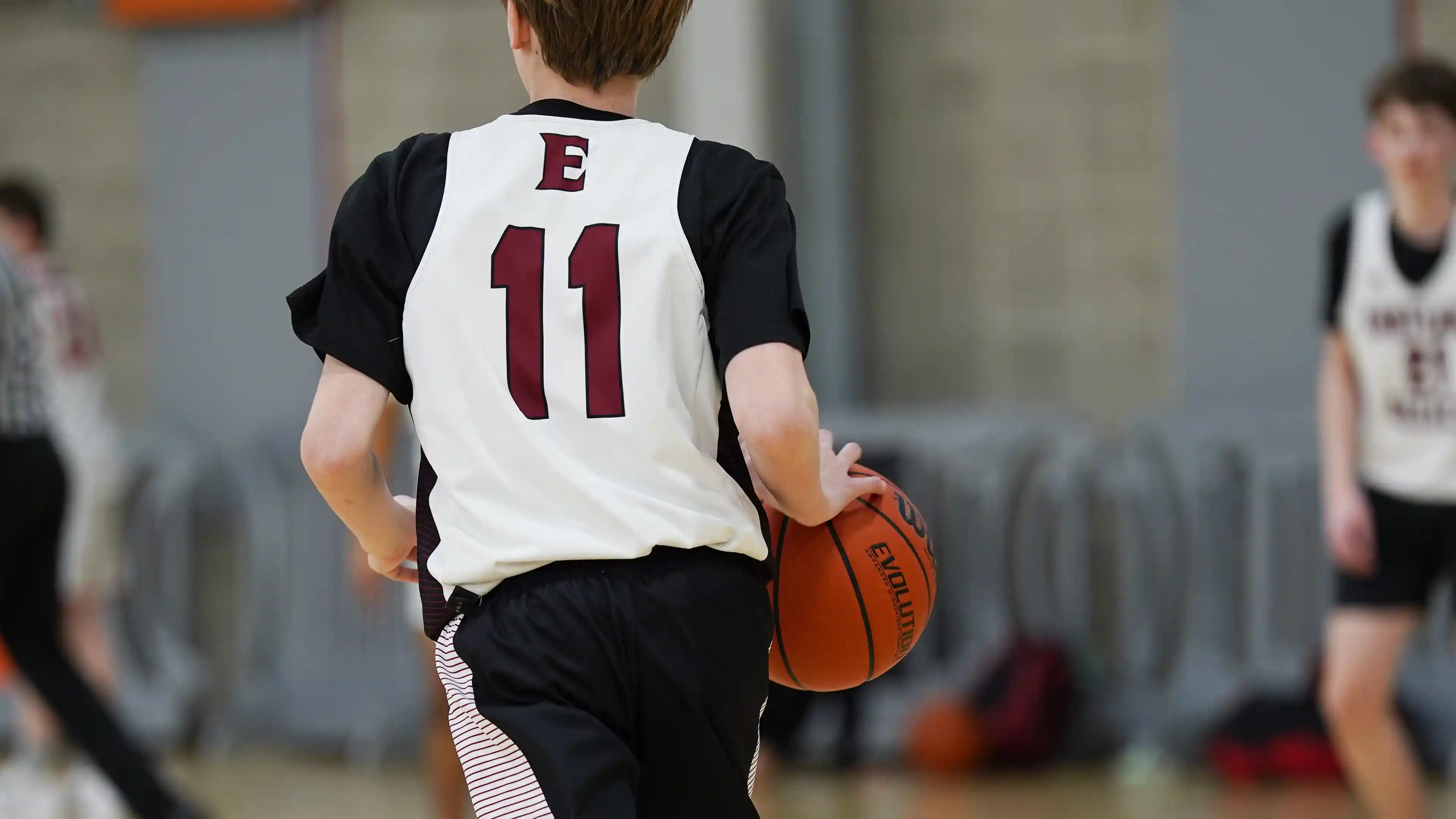 Boy dribbling a basketball up-court against a defender