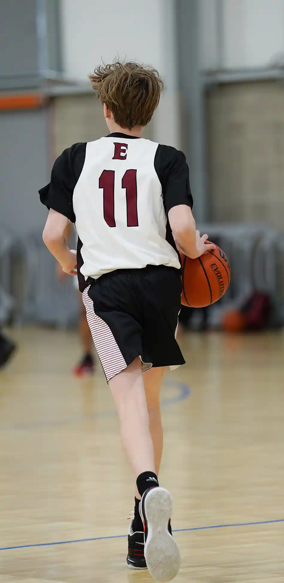 Boy dribbling a basketball up-court against a defender