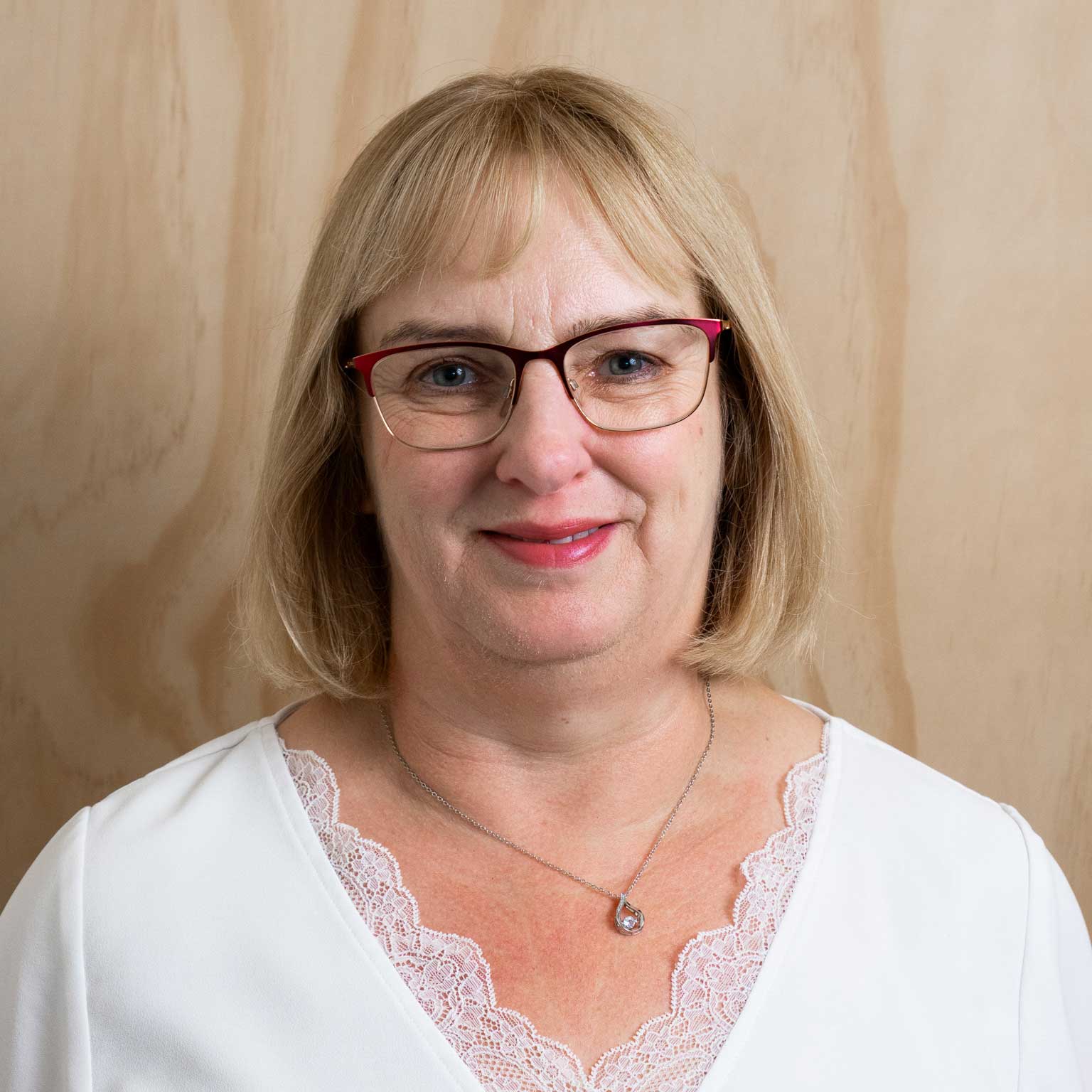 Lois smiling at the camera in front of a wooden wall