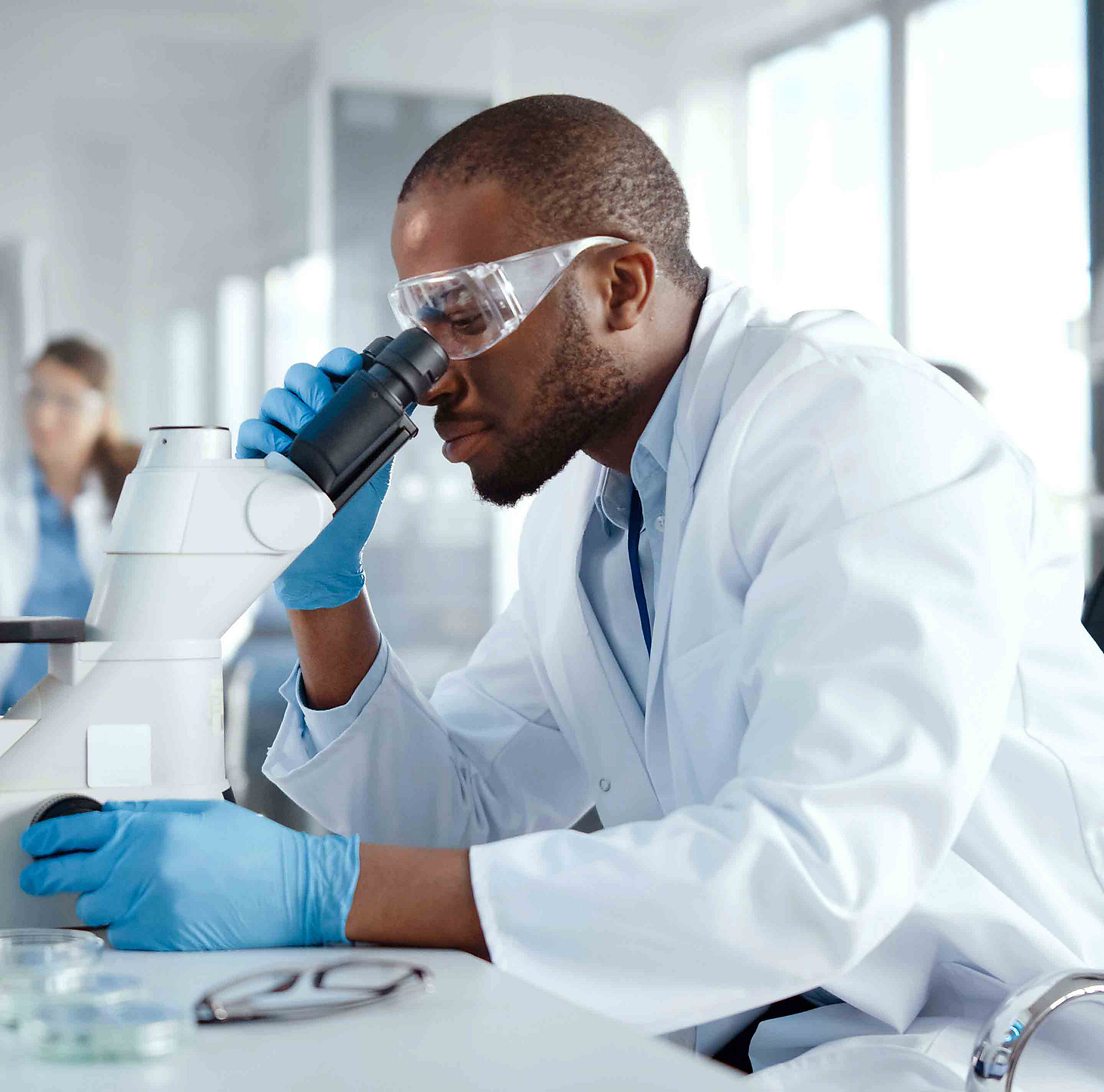 Employee in a lab using a microscope.